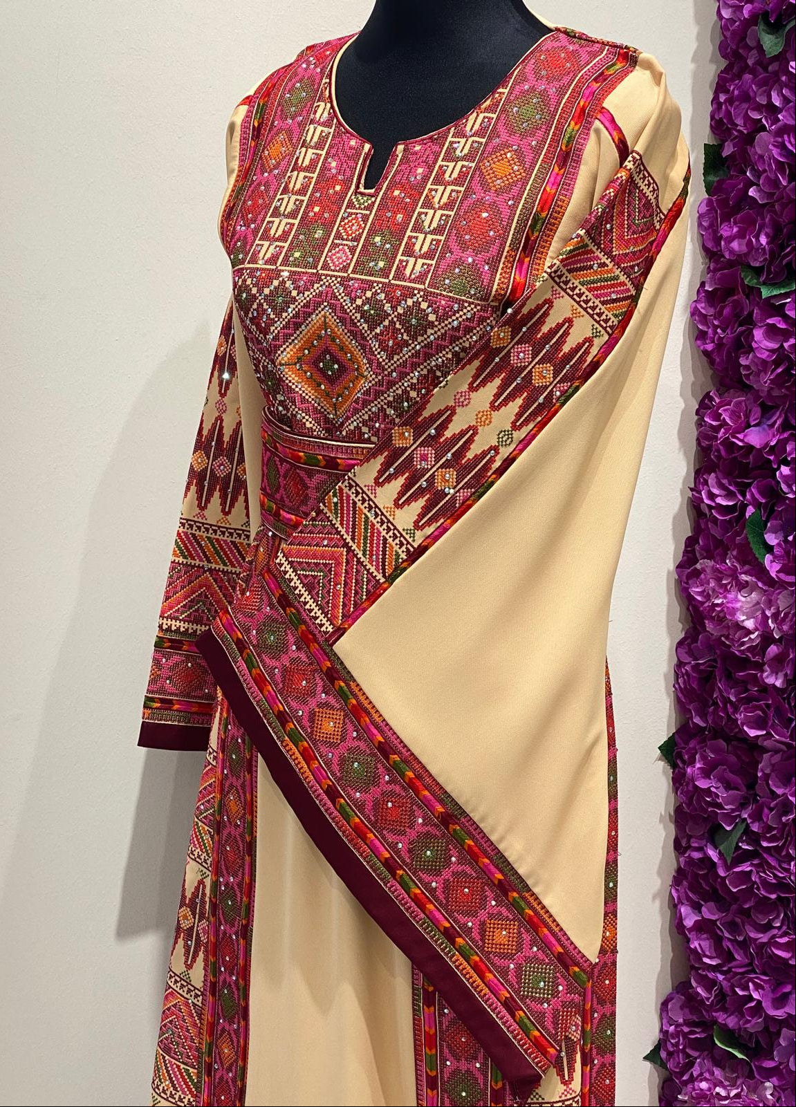 Beige Palestinian-inspired thobe with burgundy and olive green geometric embroidery at Arisca Qatar.