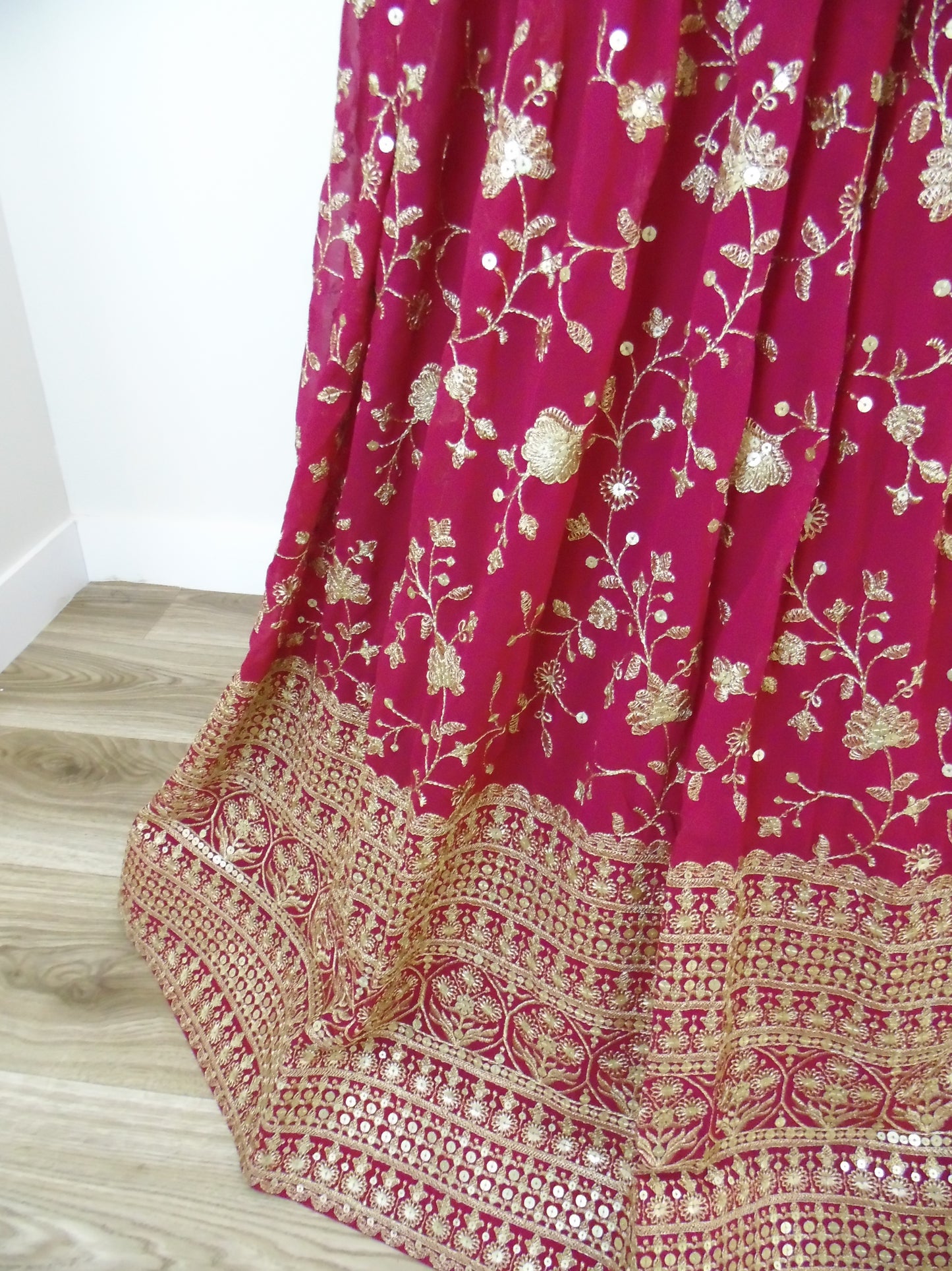 Pink fabric with gold floral patterns on a wooden surface