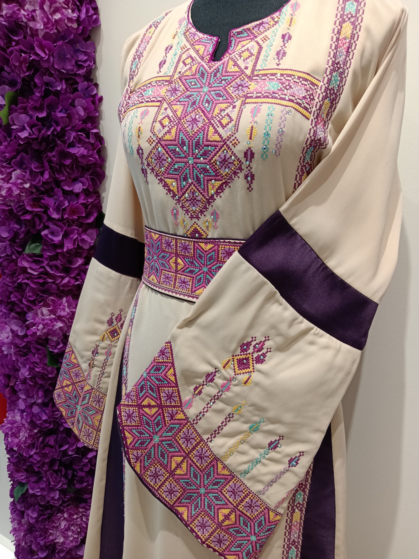 beautifully embroidered Palestinian thobe combines a soft beige tone with rich plum accents and intricate heritage-inspired embroidery