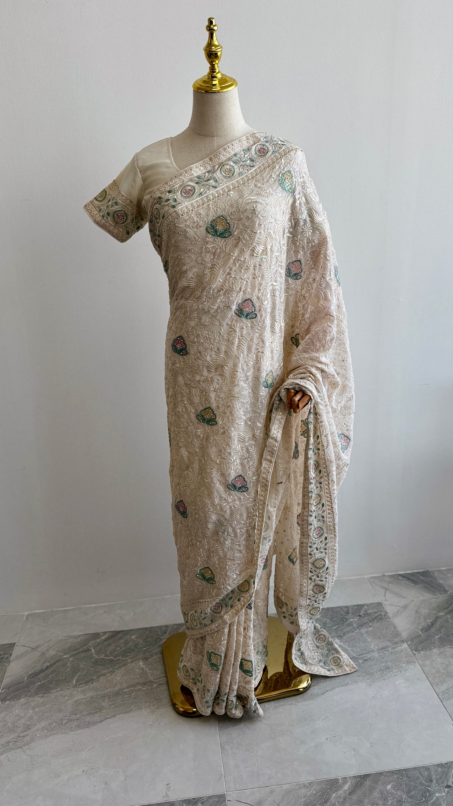 Off white Chikankari saree with floral embroidery displayed on mannequin
