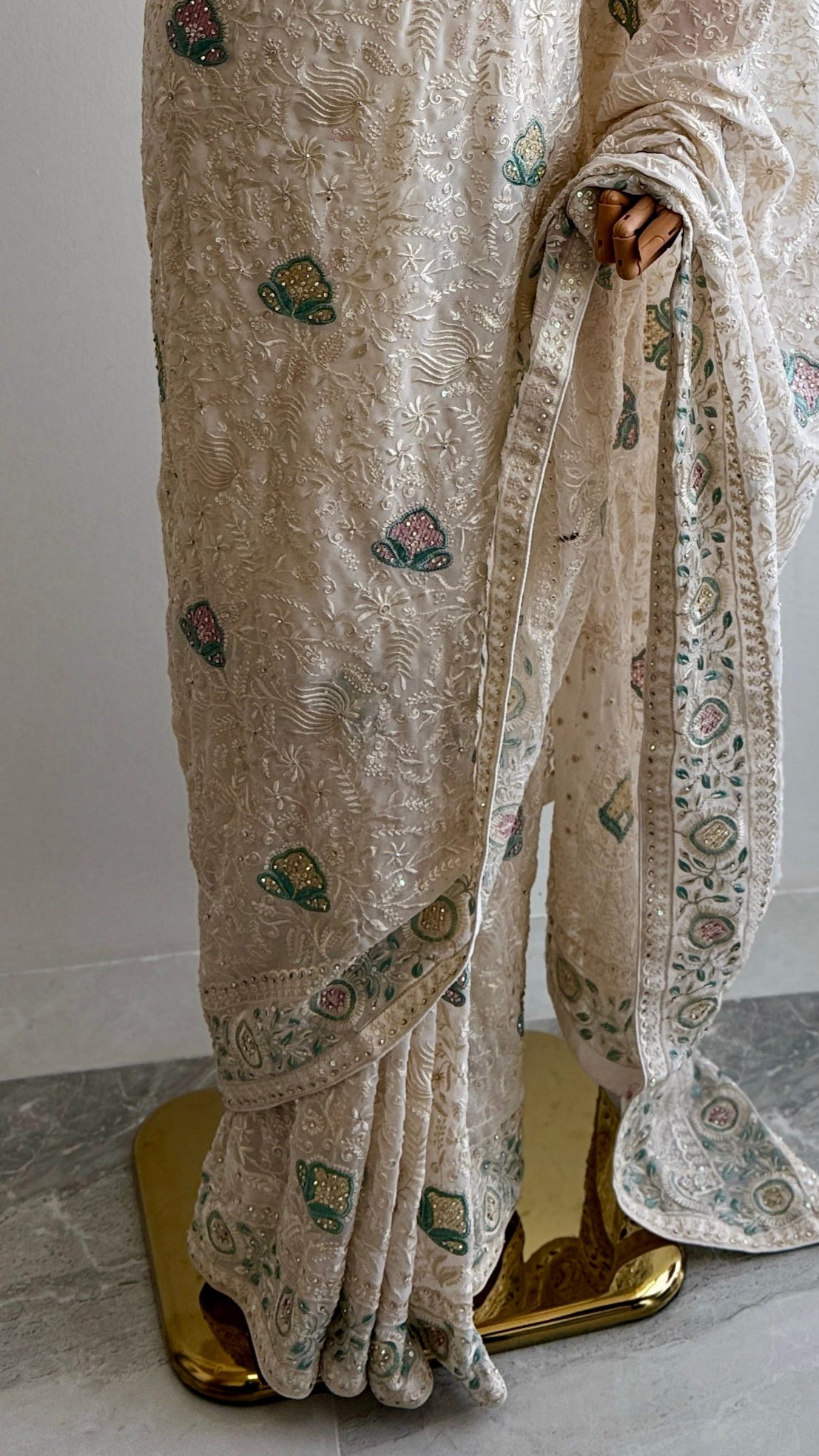 Beige saree with floral patterns on a mannequin against a white background