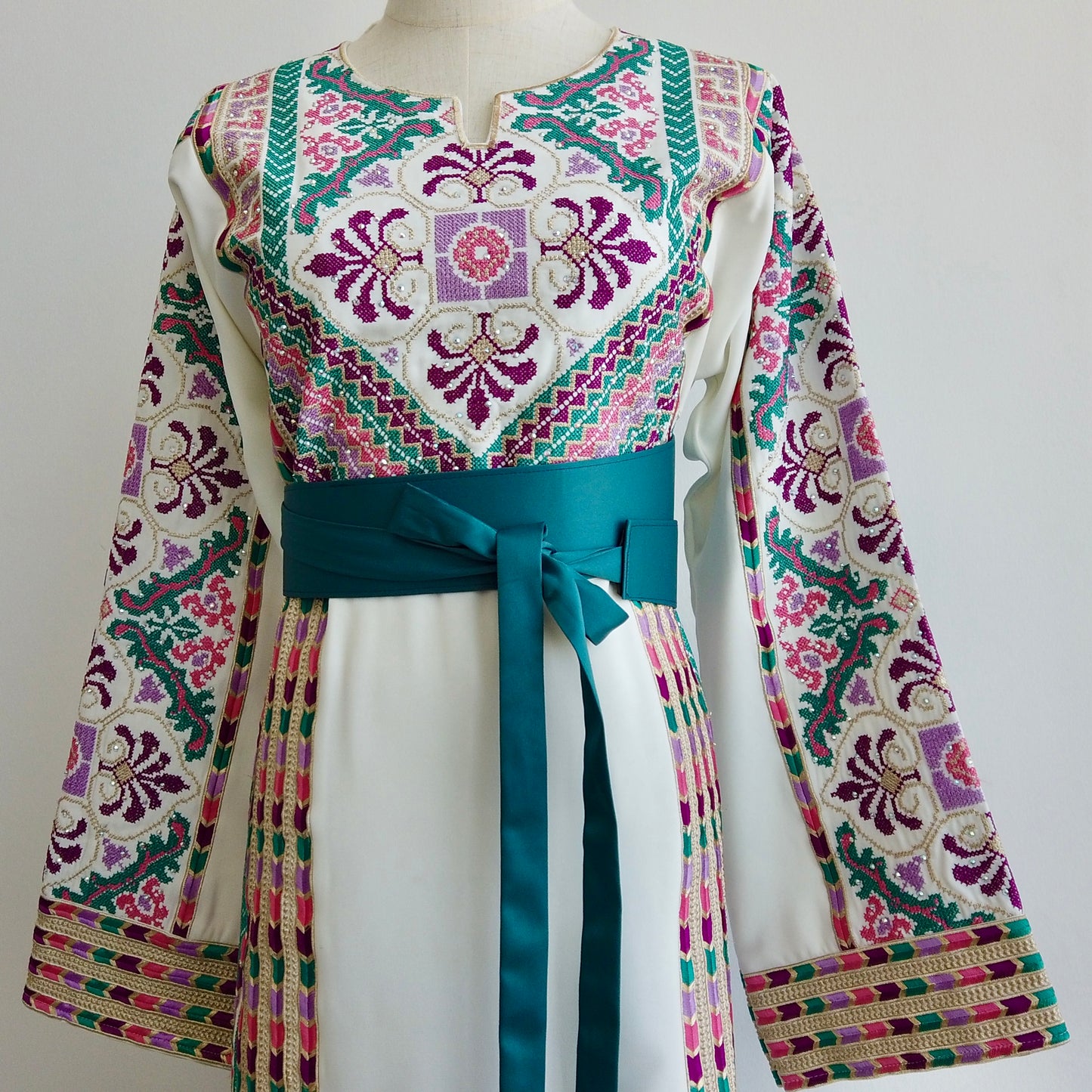 Side angle of thobe showcasing the fringe-detailed sleeves and belt accentuating the waist