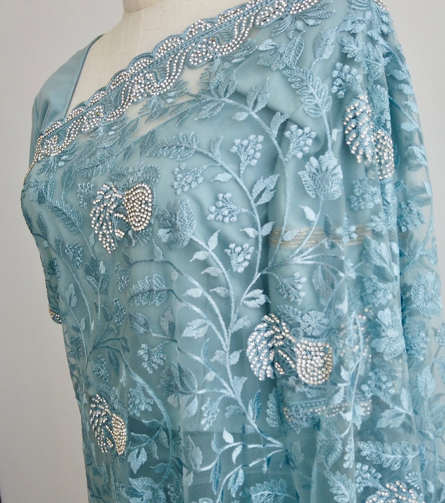 Close up of Light blue ready to wear saree with floral and leaf patterns on a mannequin against a white background