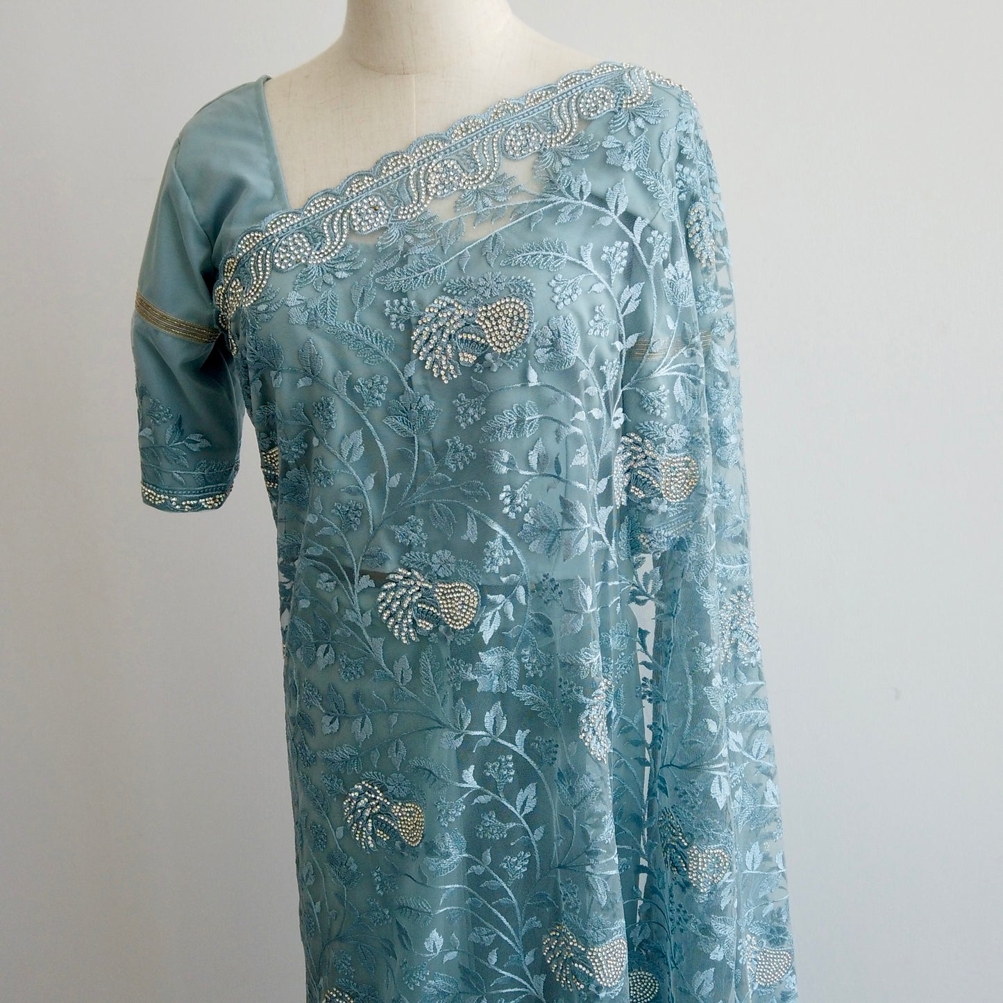 Full-length view of blue embroidered net saree showing pre-stitched pleats and elegant pallu.