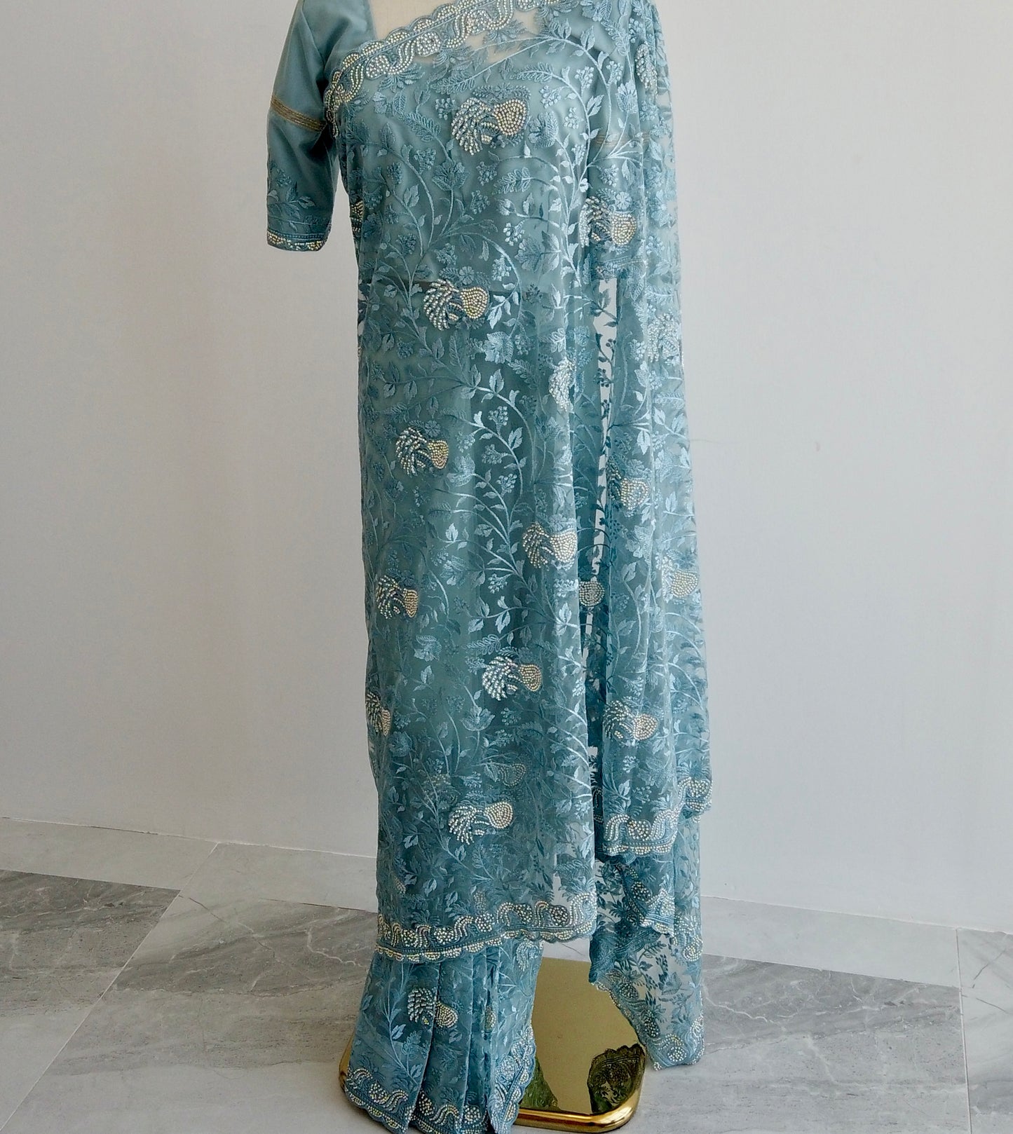Blue net ready-to-wear saree with silver floral embroidery displayed on a mannequin
