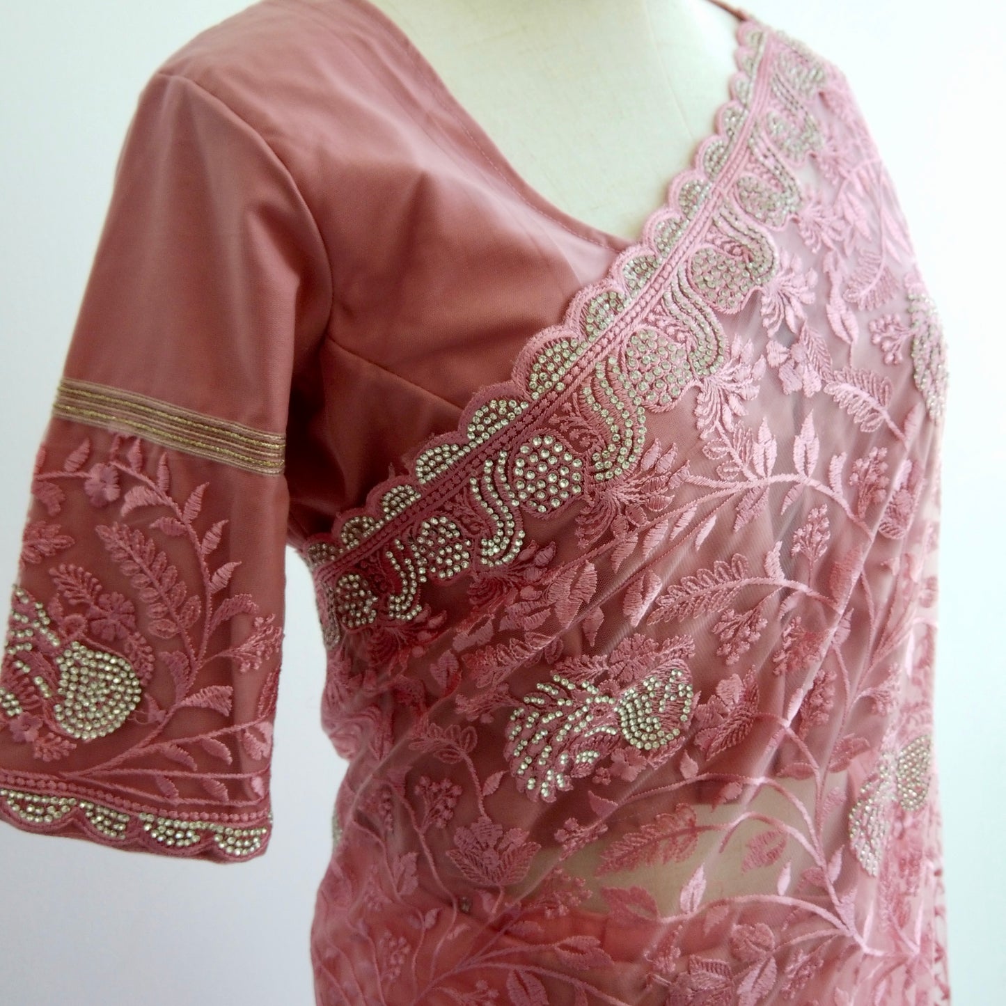 Close-up of silver thread embroidery and sequins on sheer pink net fabric