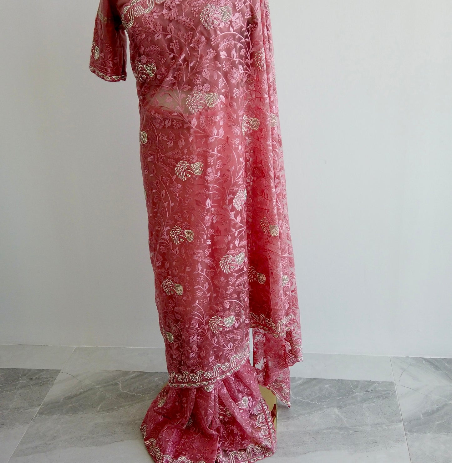Full-length view of pink embroidered net saree showing pre-stitched pleats and elegant pallu