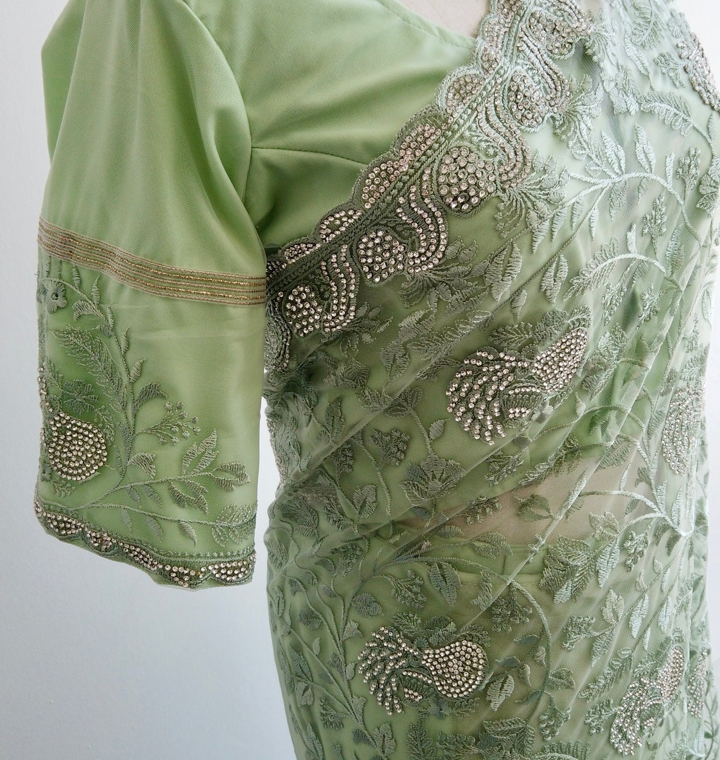 Close-up of thread embroidery and sequins on sheer green net fabric of ready to wear Saree
