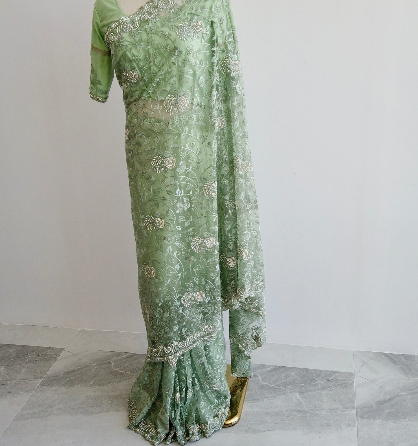 Full-length view of green embroidered net ready to wear saree showing pre-stitched pleats and elegant pallu