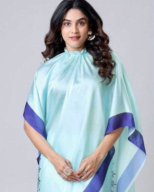 Woman wearing a light blue saree with navy border on a plain background