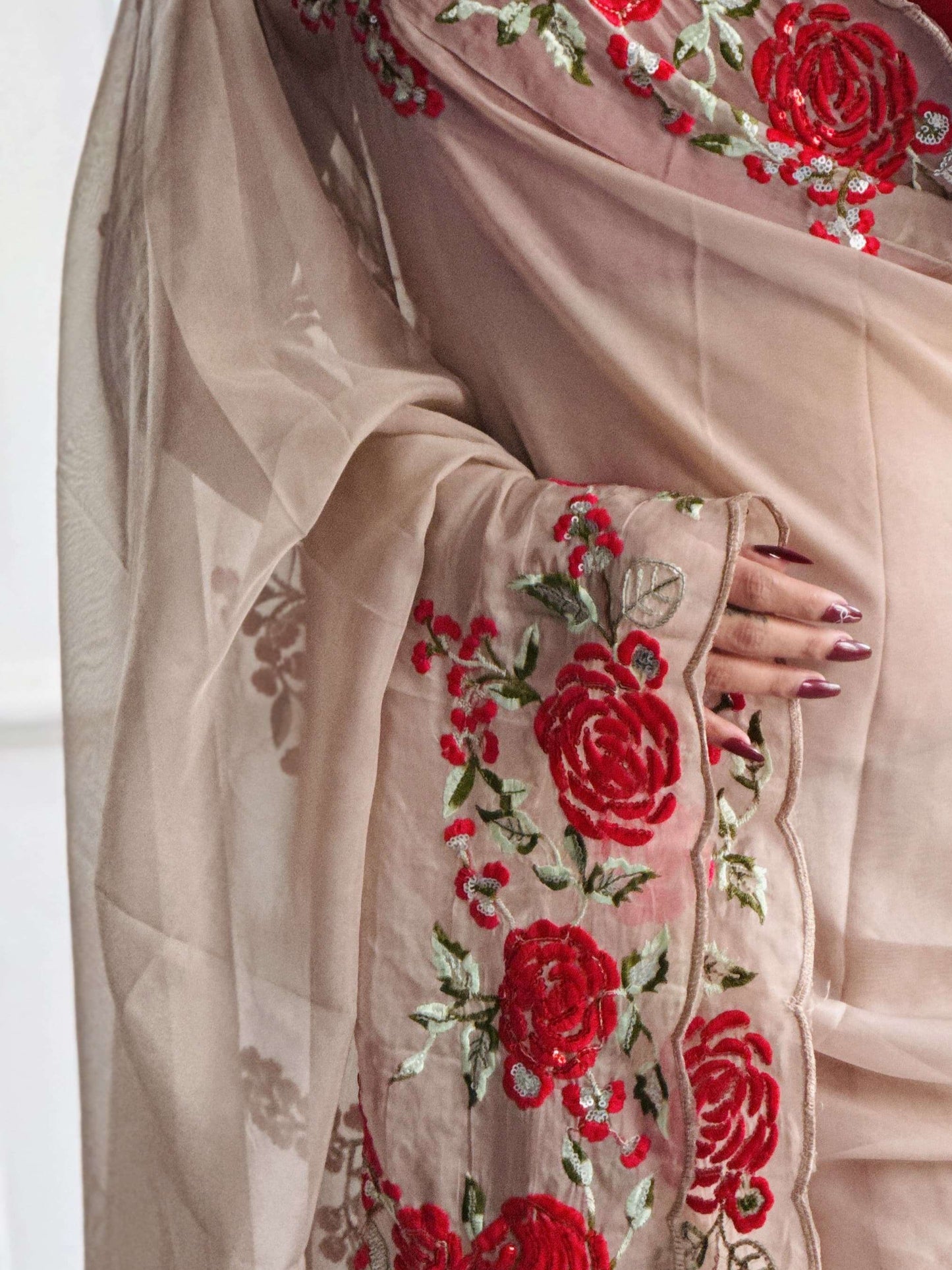 Beige saree with red floral embroidery worn by a person.