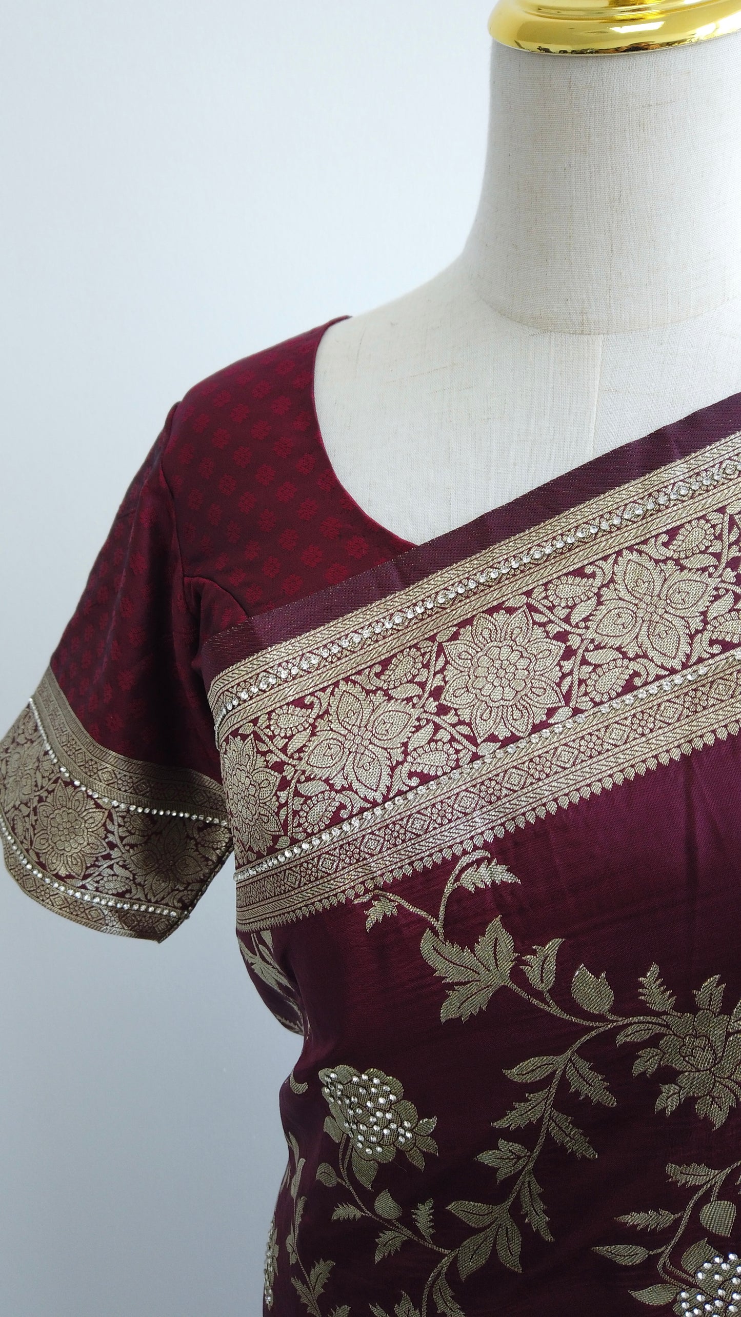 Close-up of intricate floral zari embroidery and shimmering stone work on maroon Banarasi silk fabric
