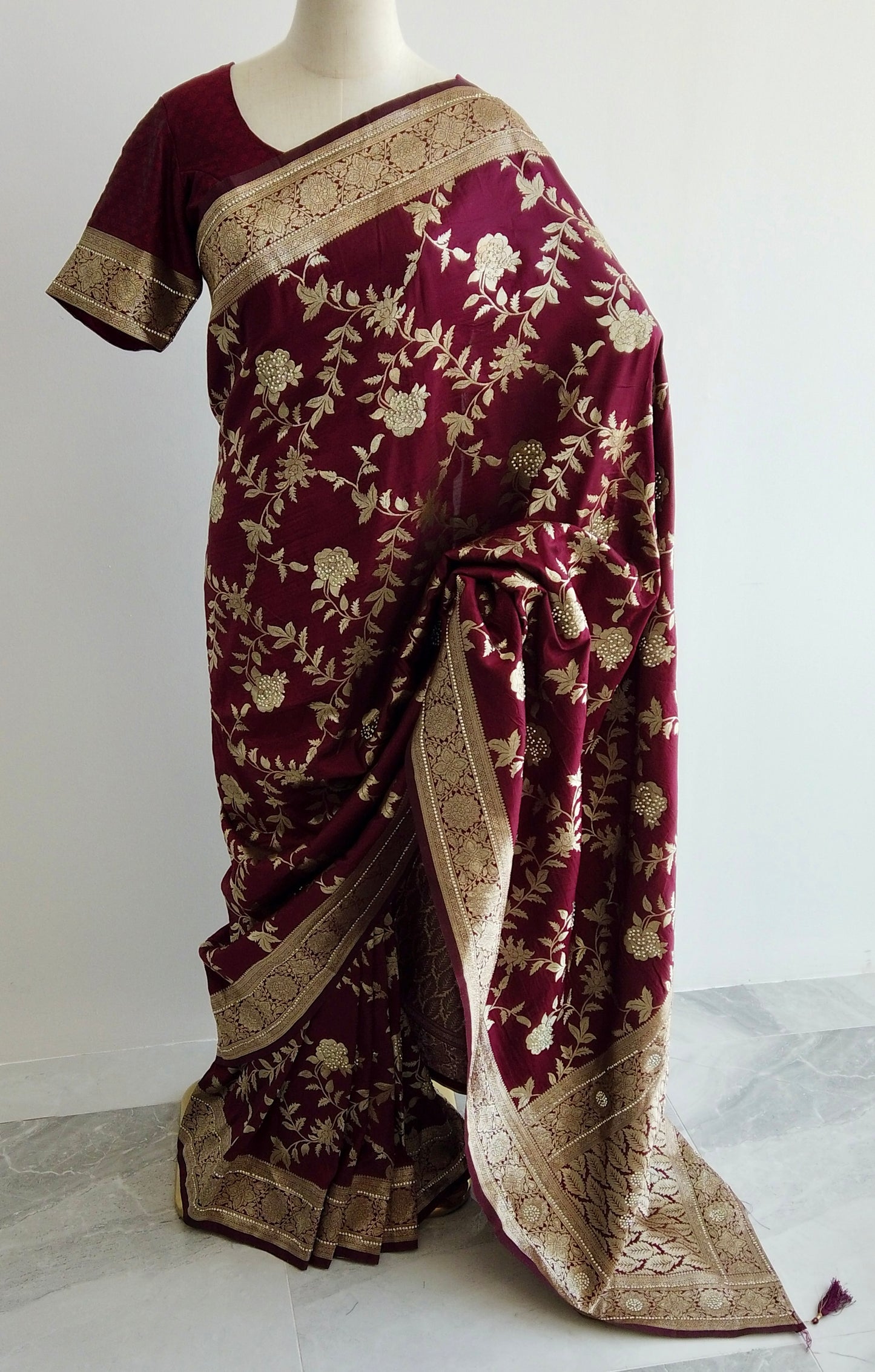 Maroon Banarasi silk ready-to-wear saree with gold floral embroidery and stone embellishments displayed on a mannequin.