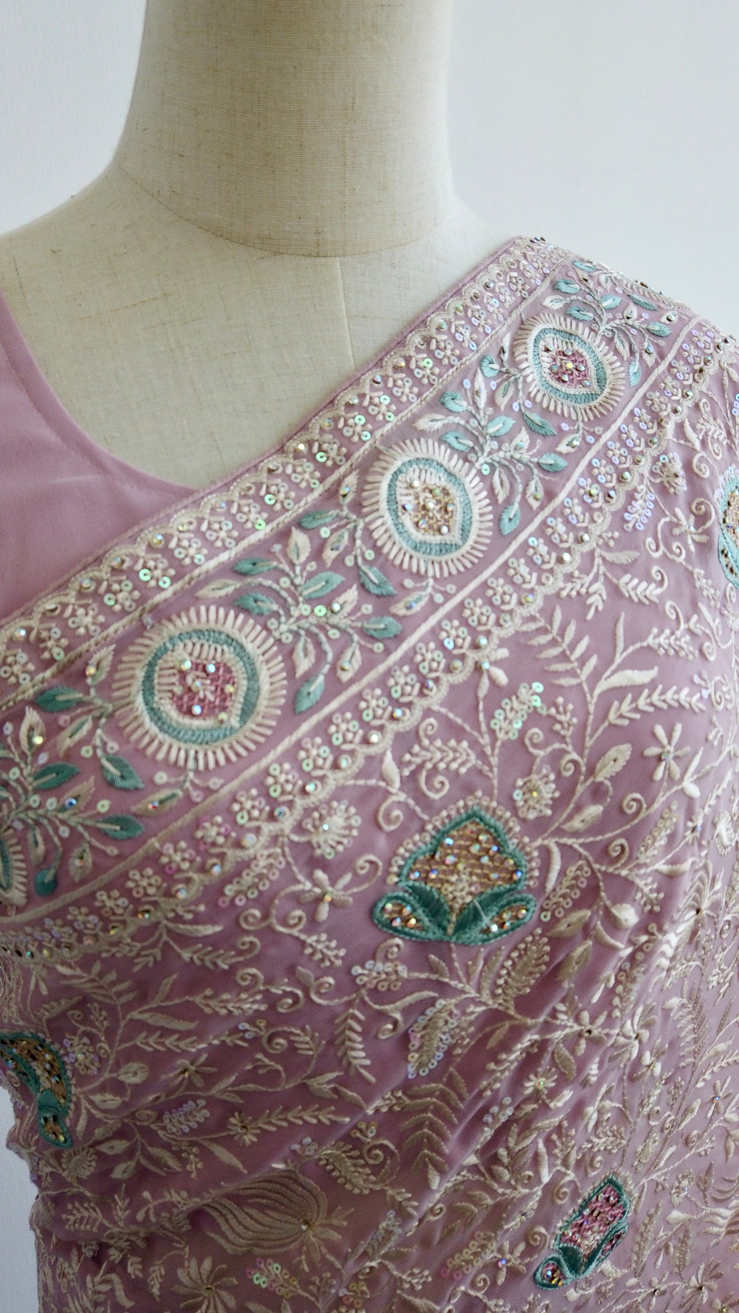 Detailed close-up of hand-embroidered Chikankari work on soft pink georgette fabric