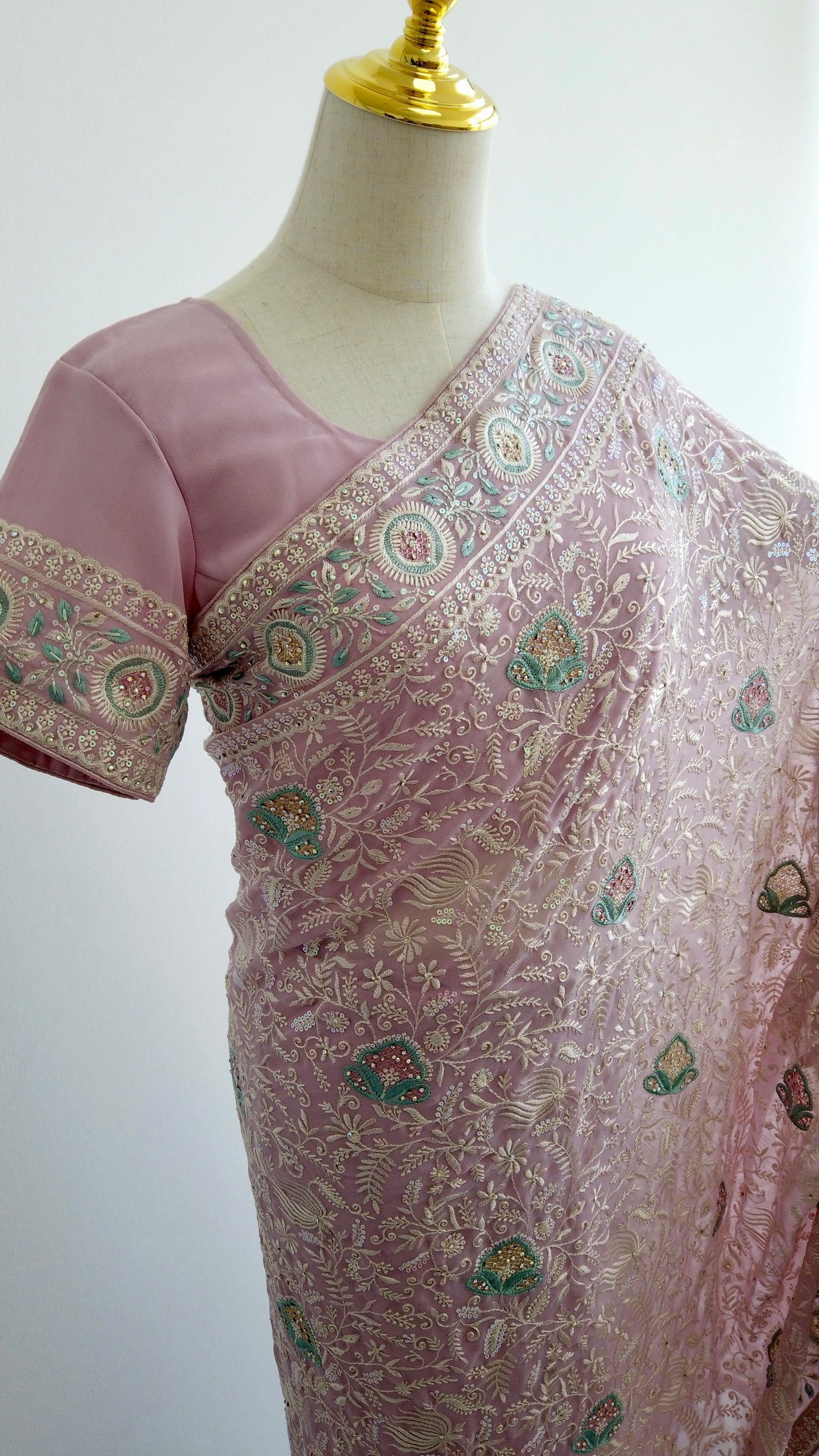 Pink saree with intricate patterns on a mannequin against a white background