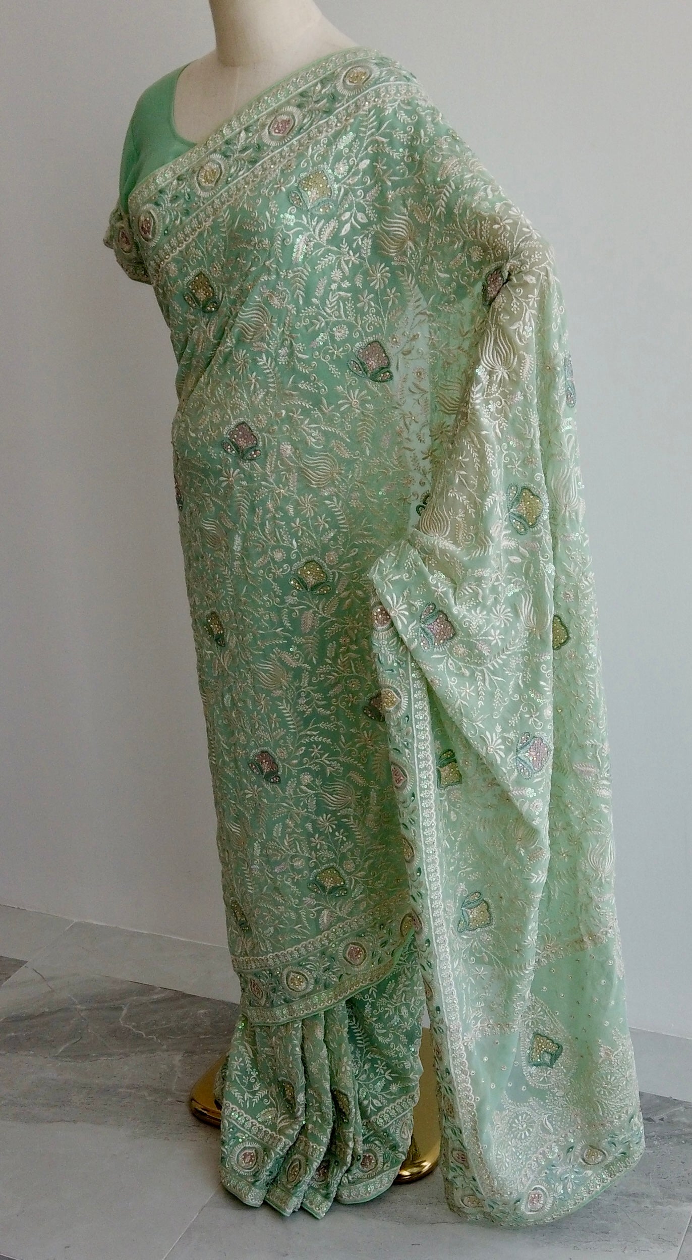 Green Chikankari saree with floral embroidery on mannequin