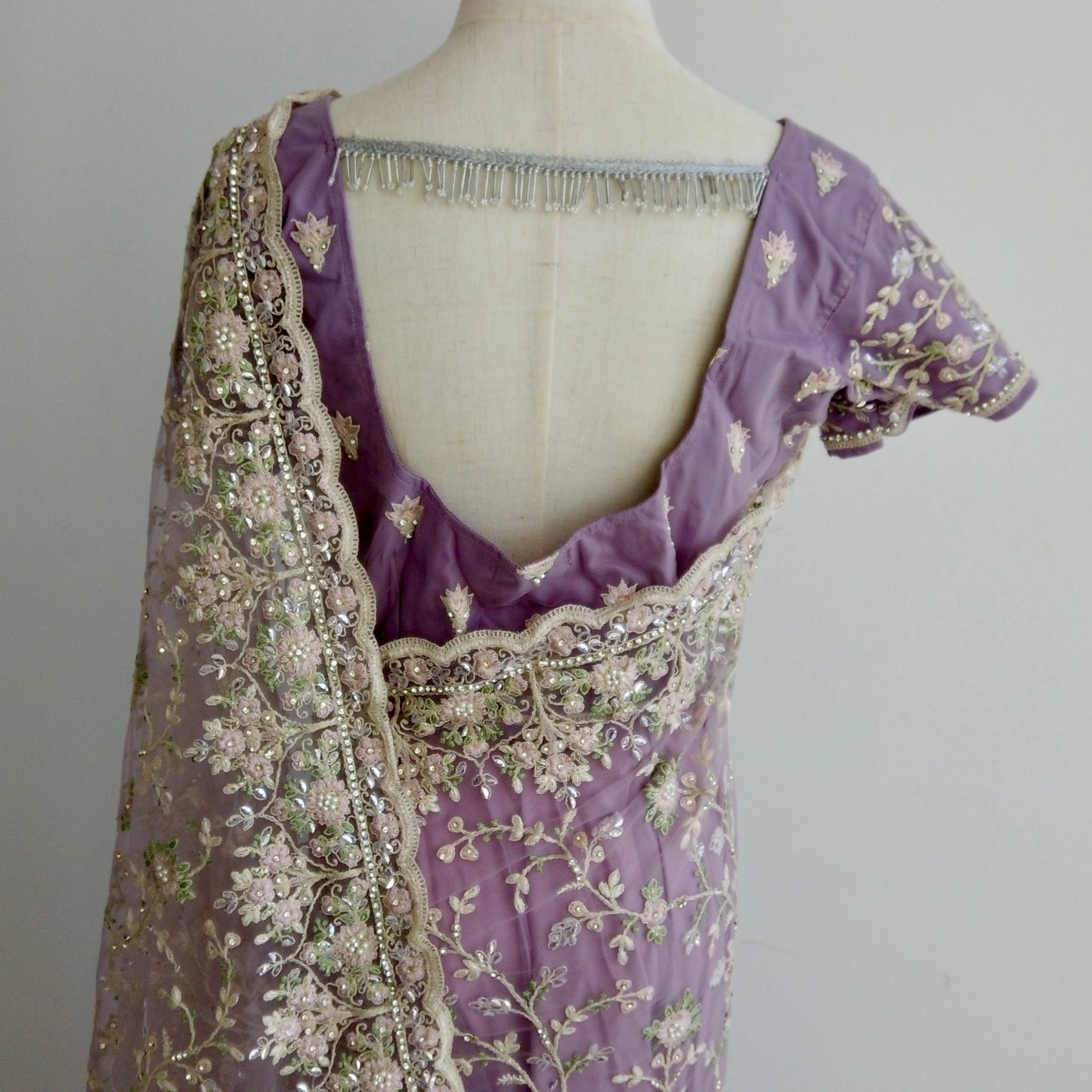 Elegant purple net saree with shimmering stone and pearl embroidery, highlighting its graceful drape and silhouette.
