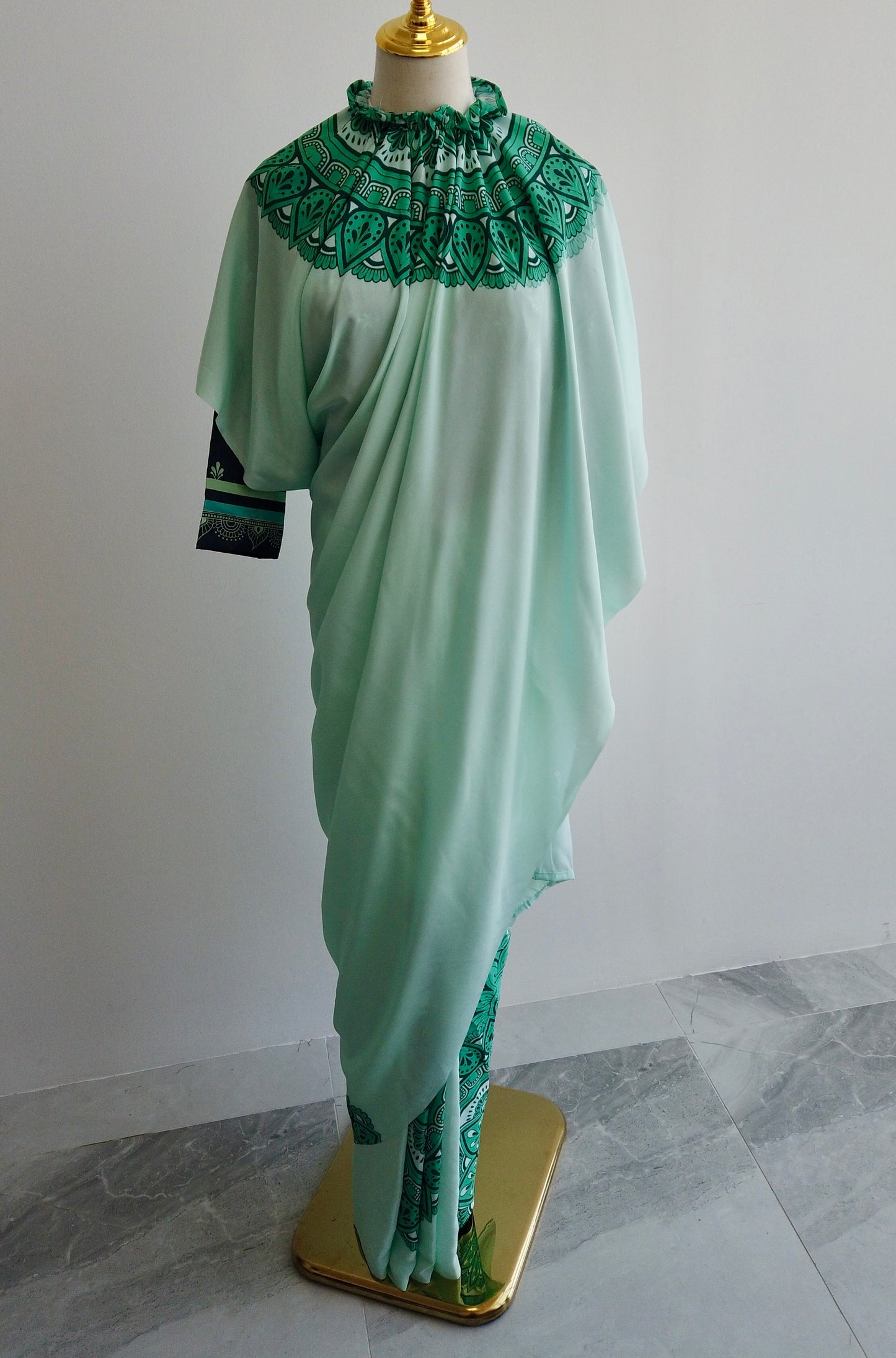Green kaftan style saree with intricate detailing on a mannequin against a plain background