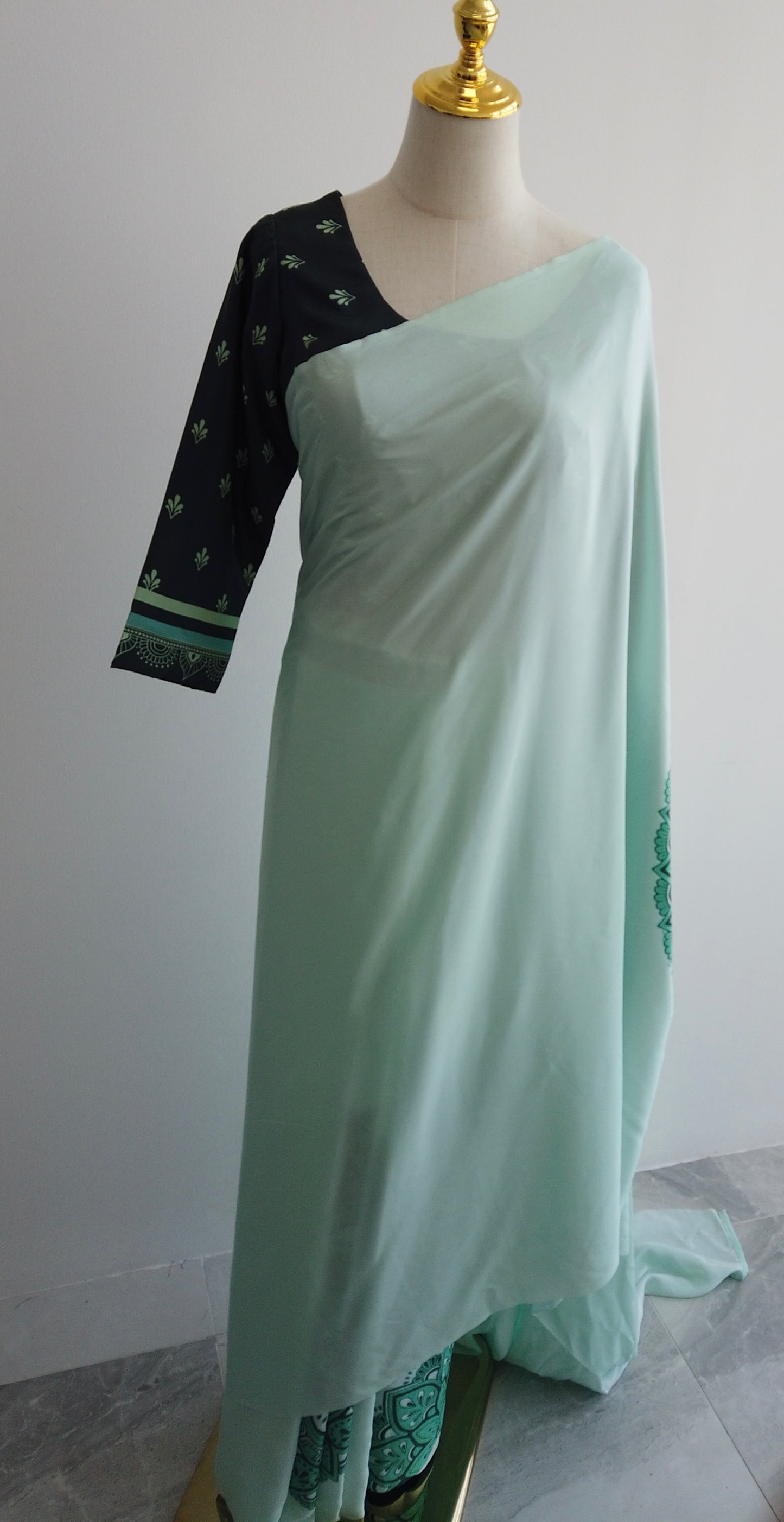 Light green saree with dark green blouse on a mannequin against a white background