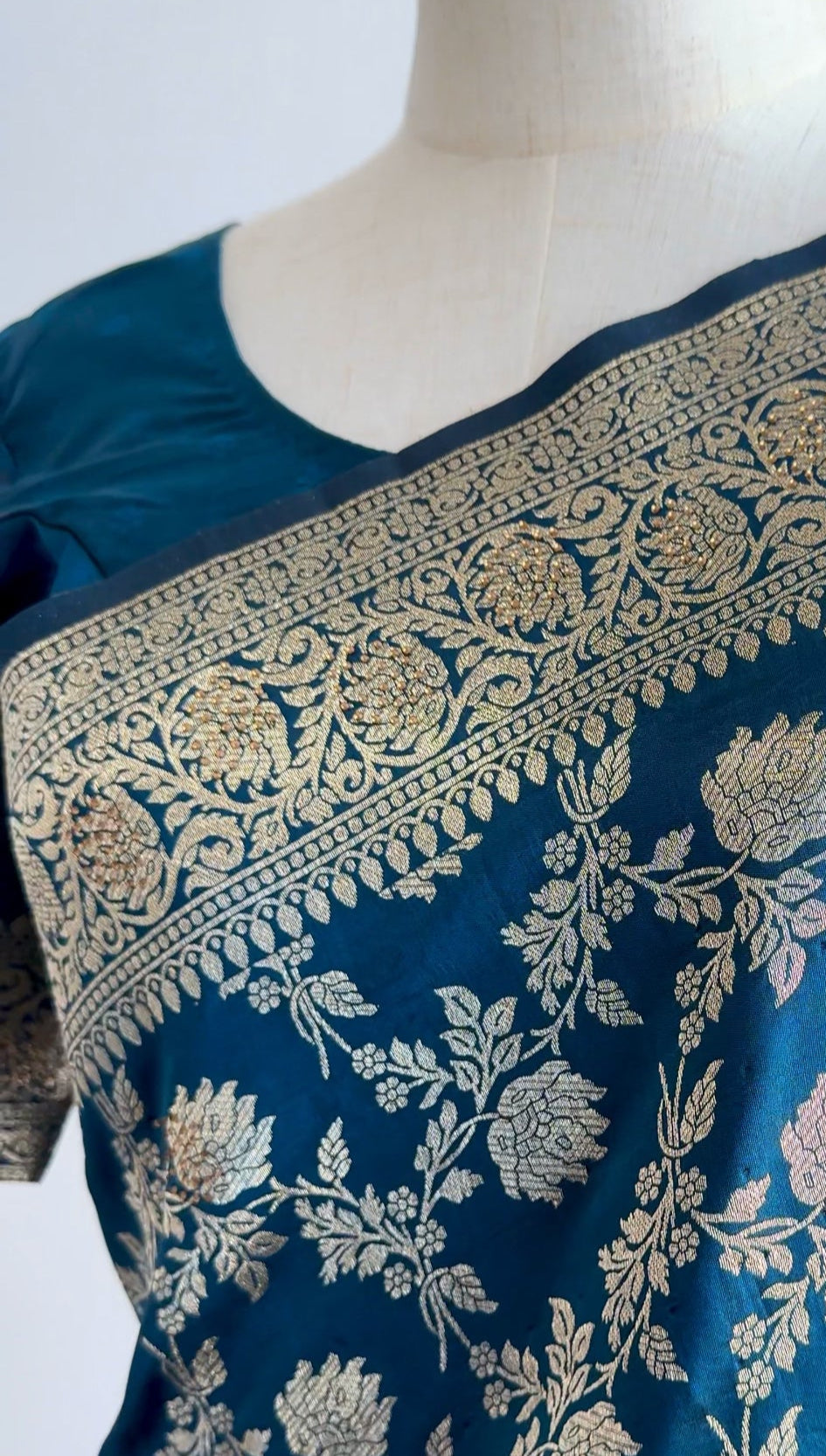 Detailed close-up of handwoven gold zari floral motifs on royal blue Banarasi silk fabric.