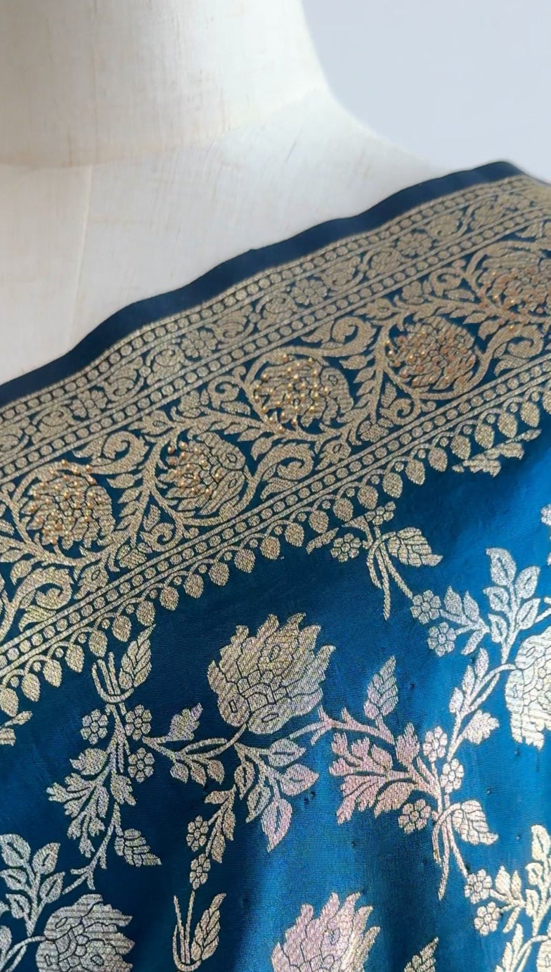Blue saree with gold floral patterns on a mannequin against a white background