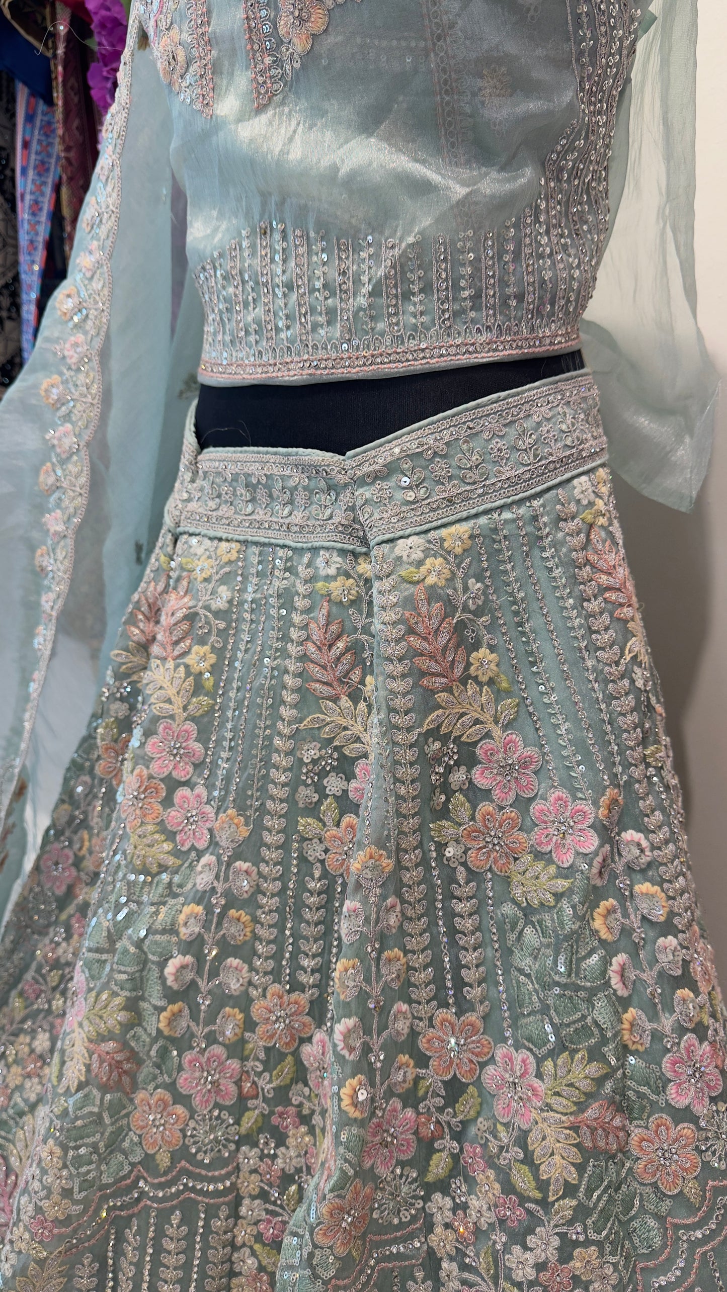 Traditional embroidered outfit with floral patterns on a light blue background