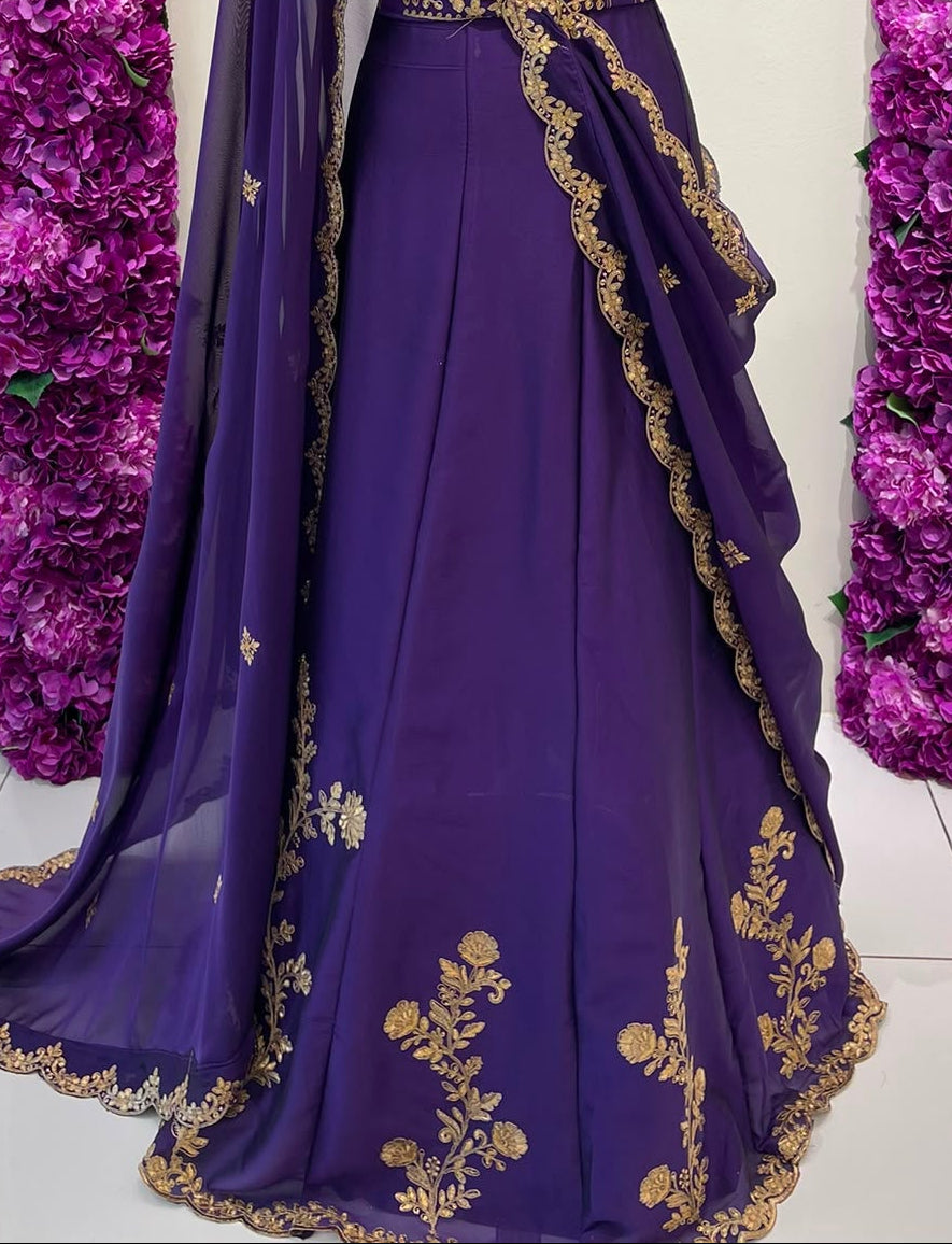 A purple traditional lehenga skirt decorated with gold embroidery and a matching sheer dupatta. .