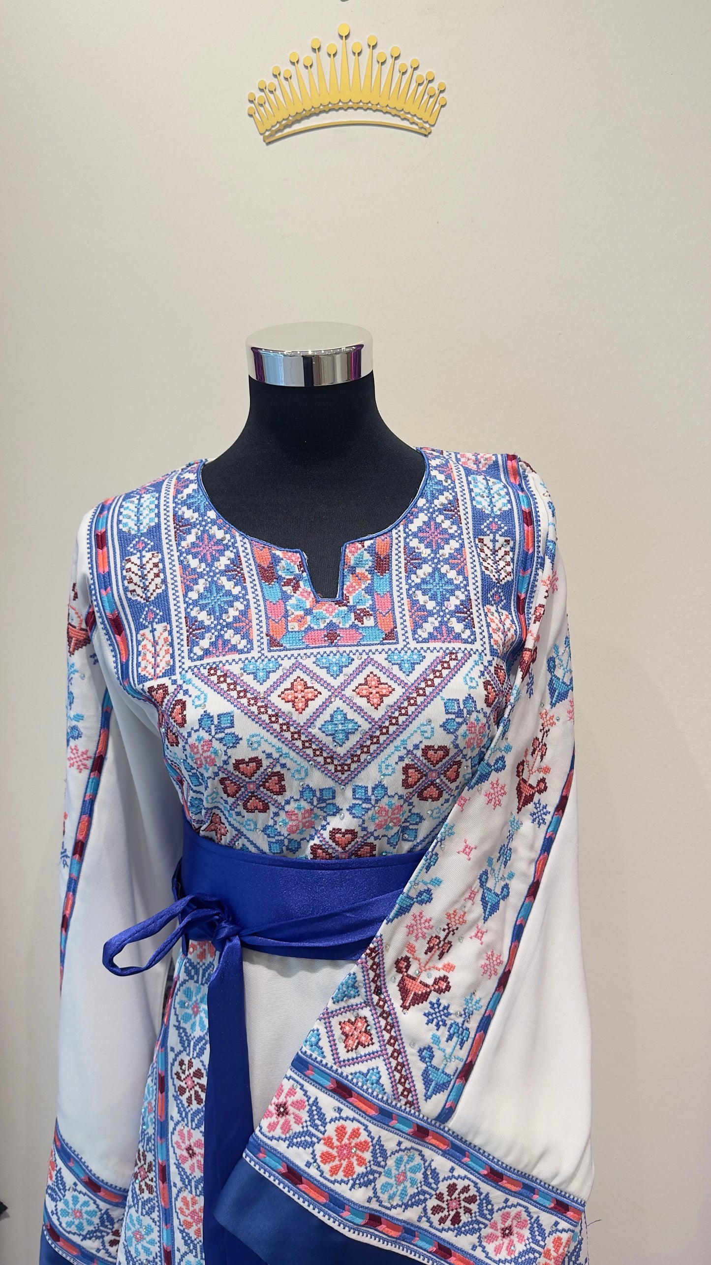 Mannequin wearing a blue and white thobe with a white scarf on a gray background