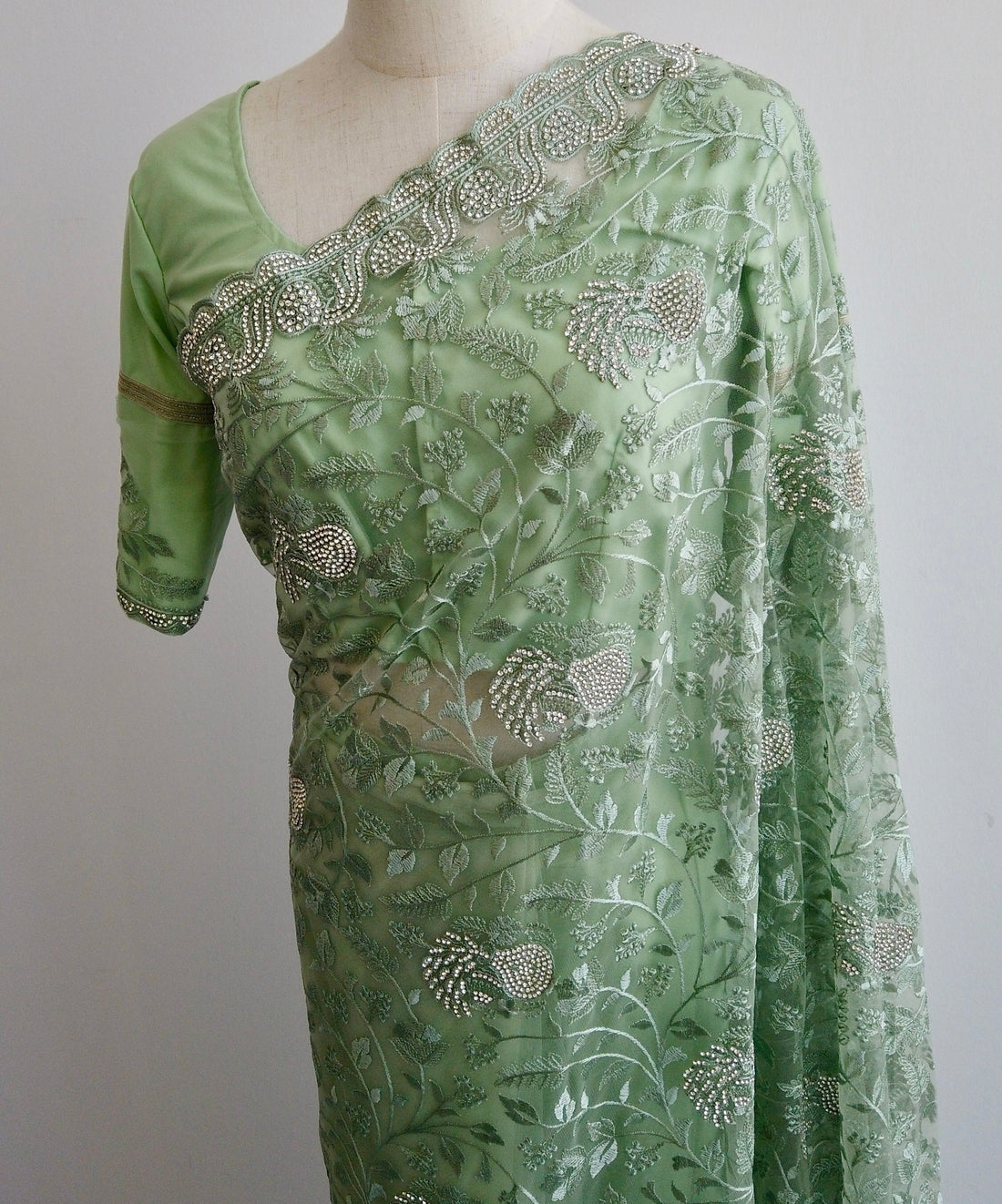Green ready to wear Saree with embroidery and white stonework on a mannequin