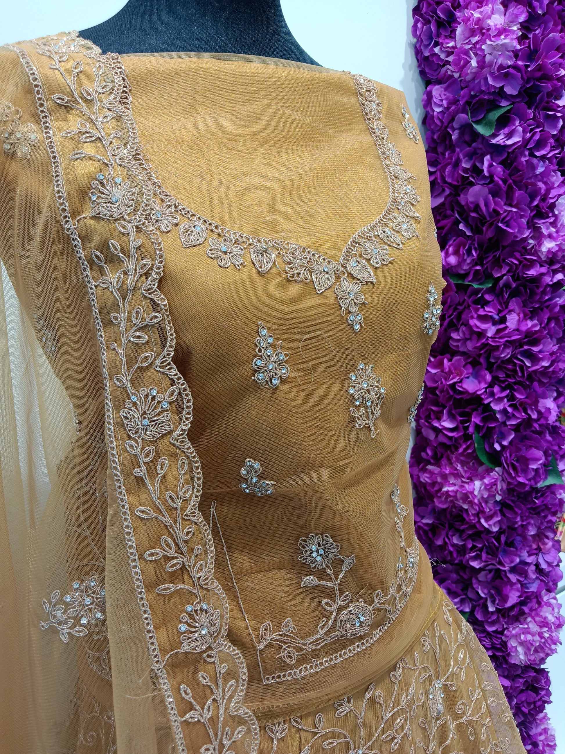 Party wear lehenga crafted from a premium silk-blend or satin silk fabric, richly adorned with intricate gold zari embroidery, sequins, and bead embellishments.