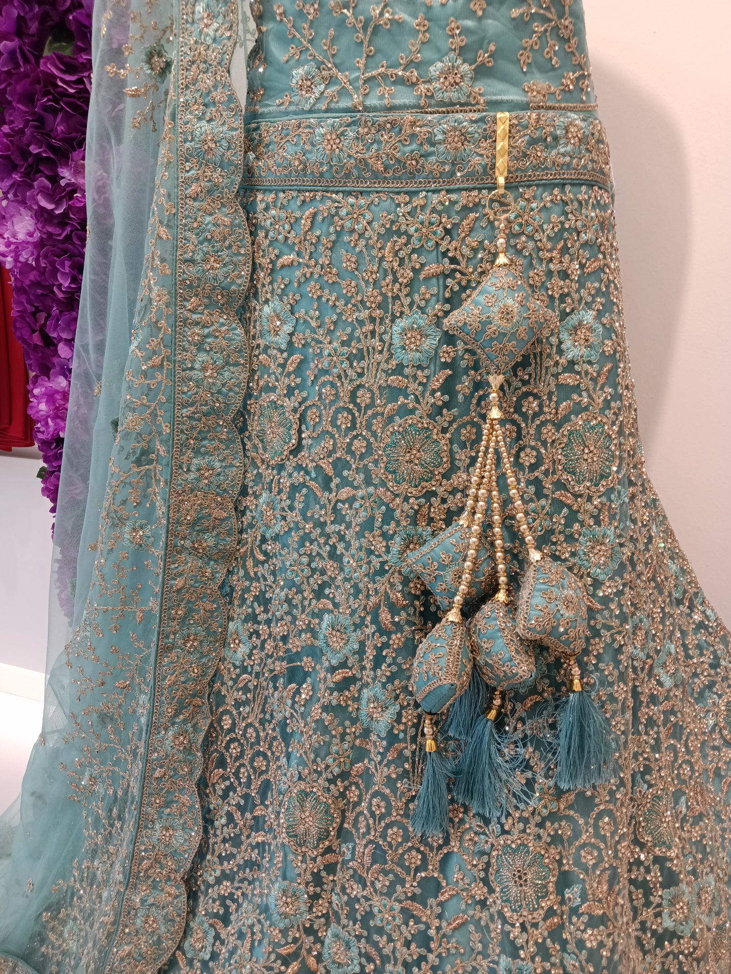 • Lehenga Skirt: Heavy embroidered net with all-over zari and stone jaal
• Blouse: Silk with embroidered neckline and inner lining 
• Dupatta: Aqua net dupatta with scalloped gold border