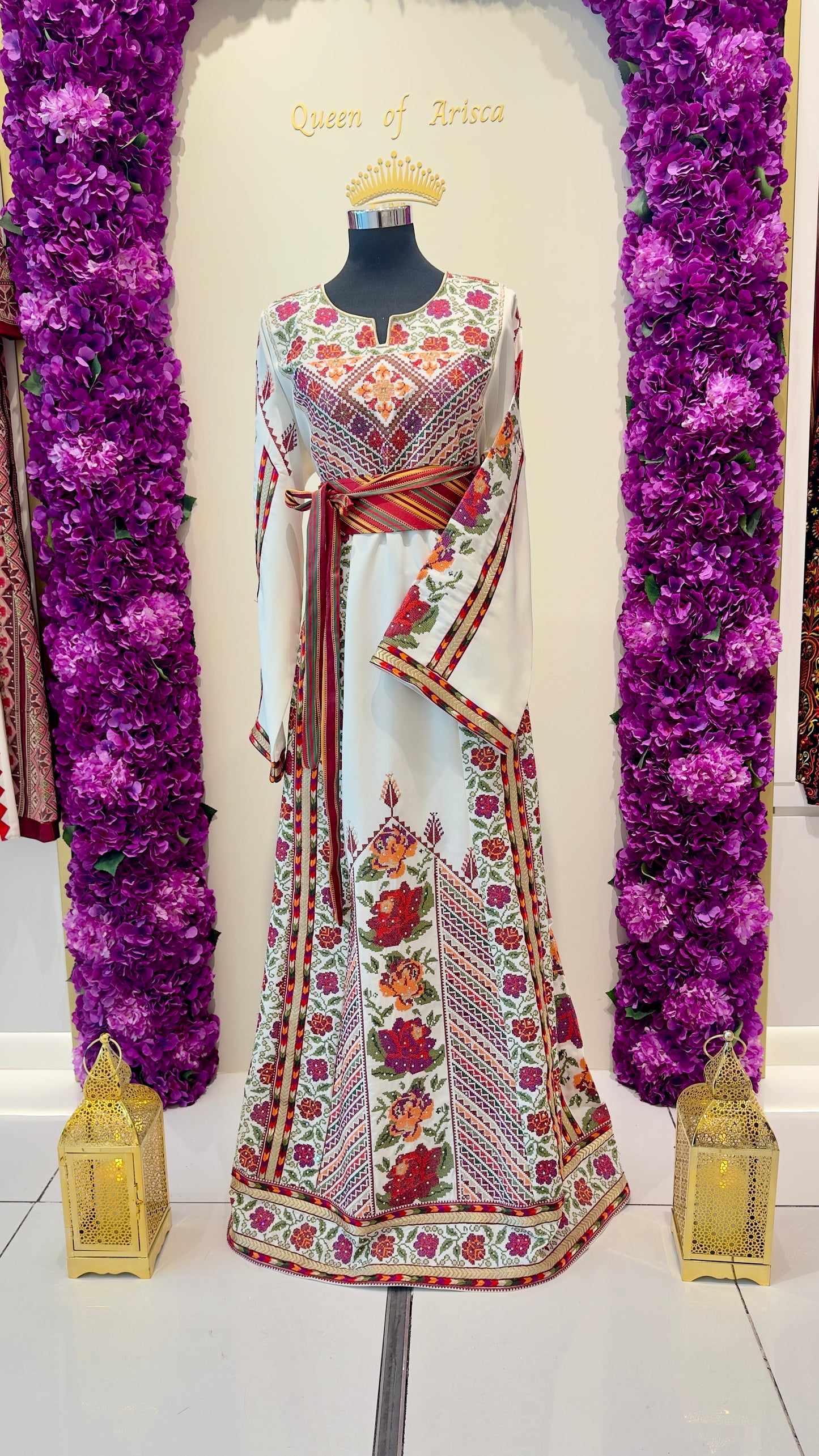 Traditional embroidered outfit on a mannequin with purple floral decorations and 'Queen of Hearts' text.