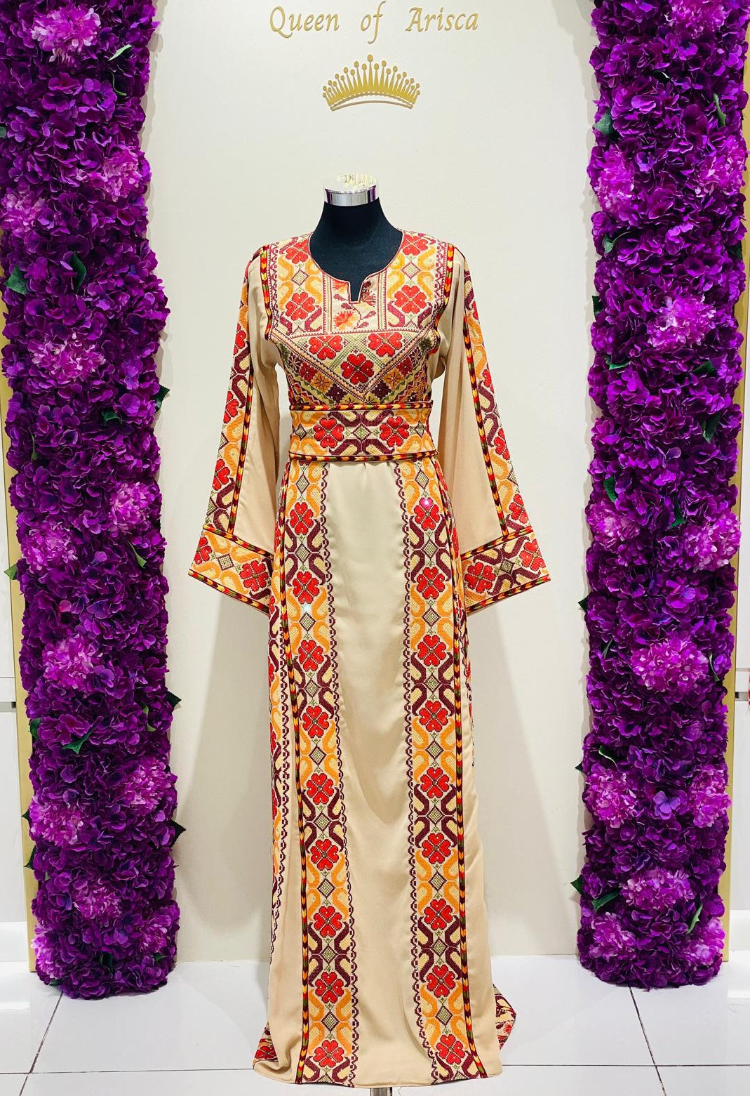 Champagne beige Palestinian-inspired thobe with red and orange geometric embroidery at Arisca Qatar.