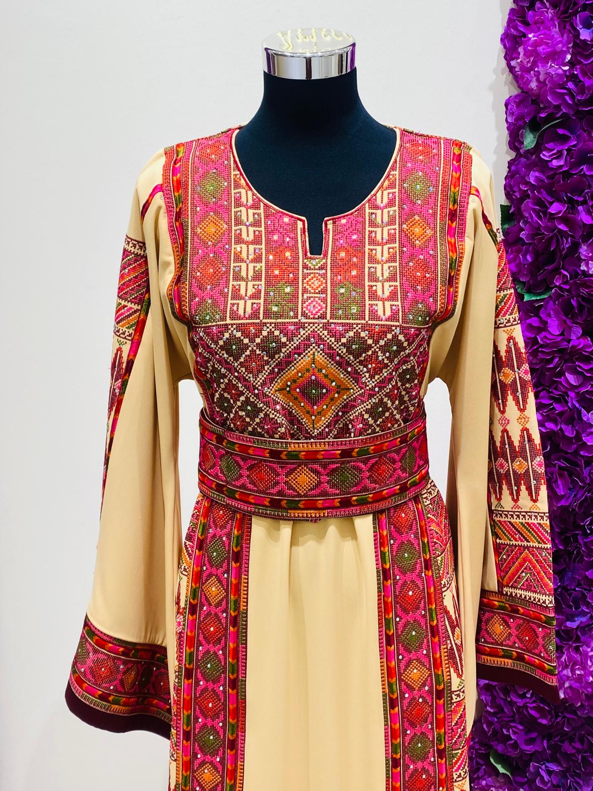Beige Palestinian-inspired thobe with burgundy and olive green geometric embroidery at Arisca Qatar.