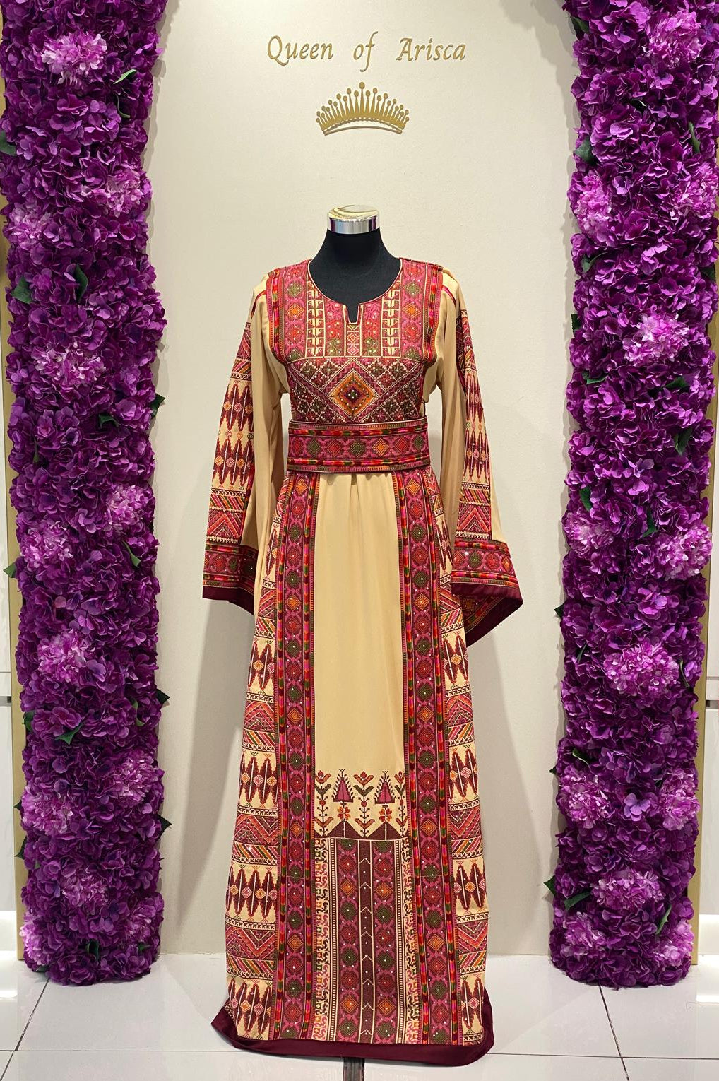 Beige Palestinian-inspired thobe with burgundy and olive green geometric embroidery at Arisca Qatar.