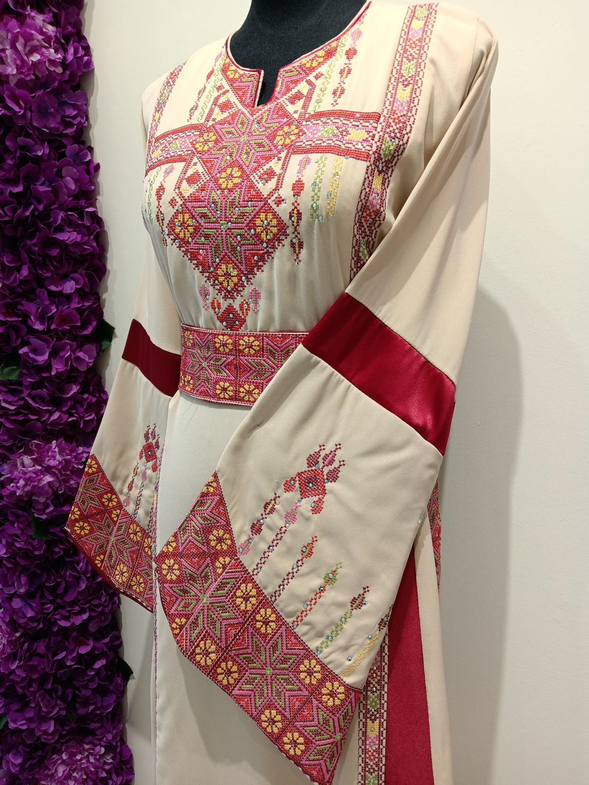 Traditional embroidered dress with red accents .