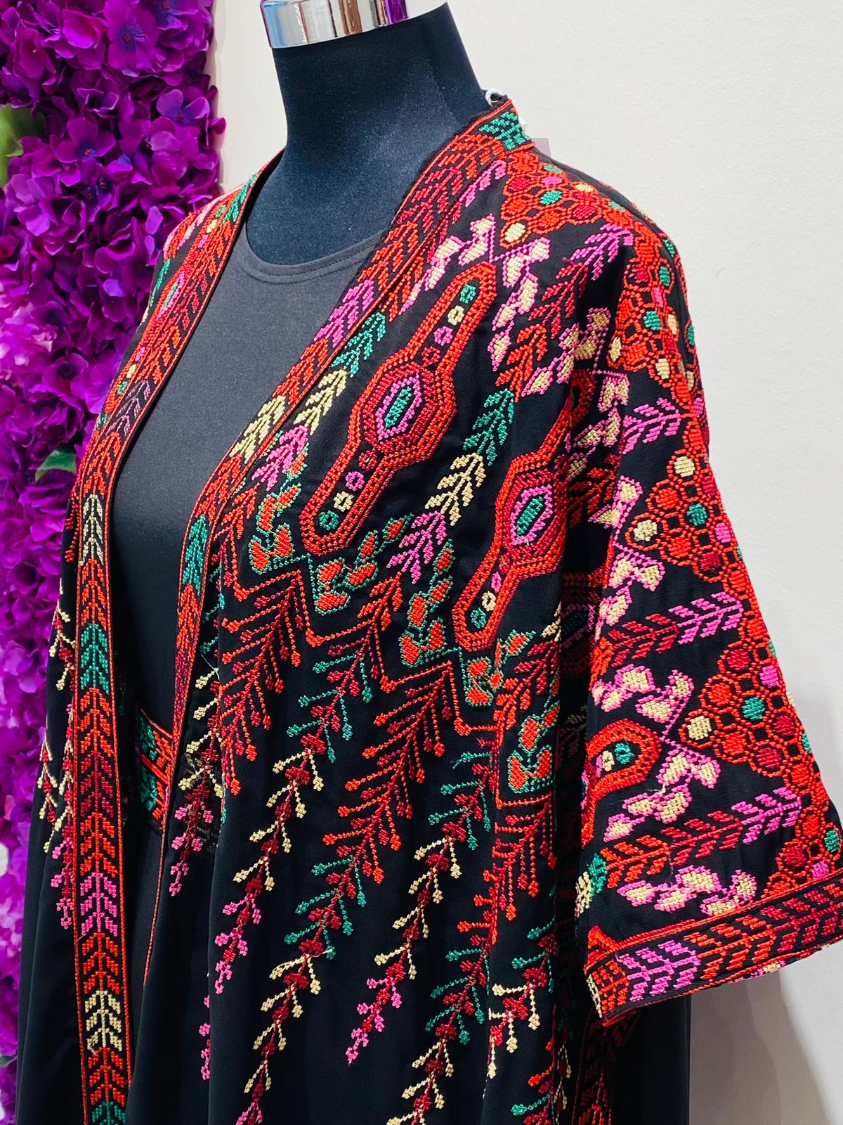 Elegant black Palestinian thobe, beautifully detailed with vibrant red and green geometric embroidery.
