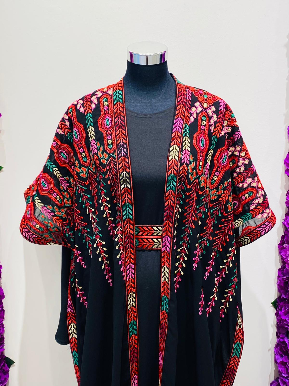 Elegant black Palestinian thobe, beautifully detailed with vibrant red and green geometric embroidery.