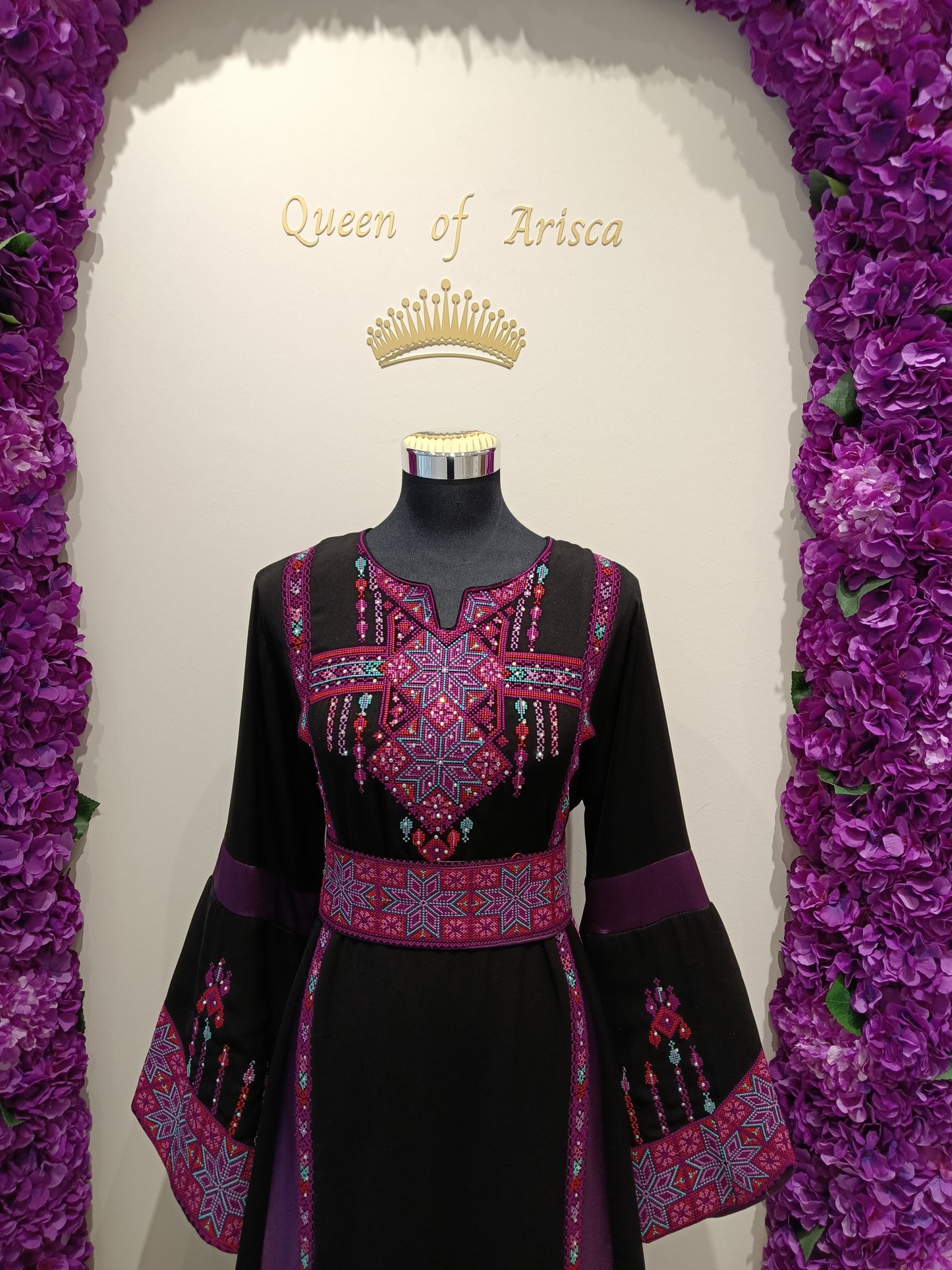 luxurious Palestinian thobe crafted from premium soft-flowing fabric in classic black, accented with rich purple panels and detailed pink-purple embroidery.