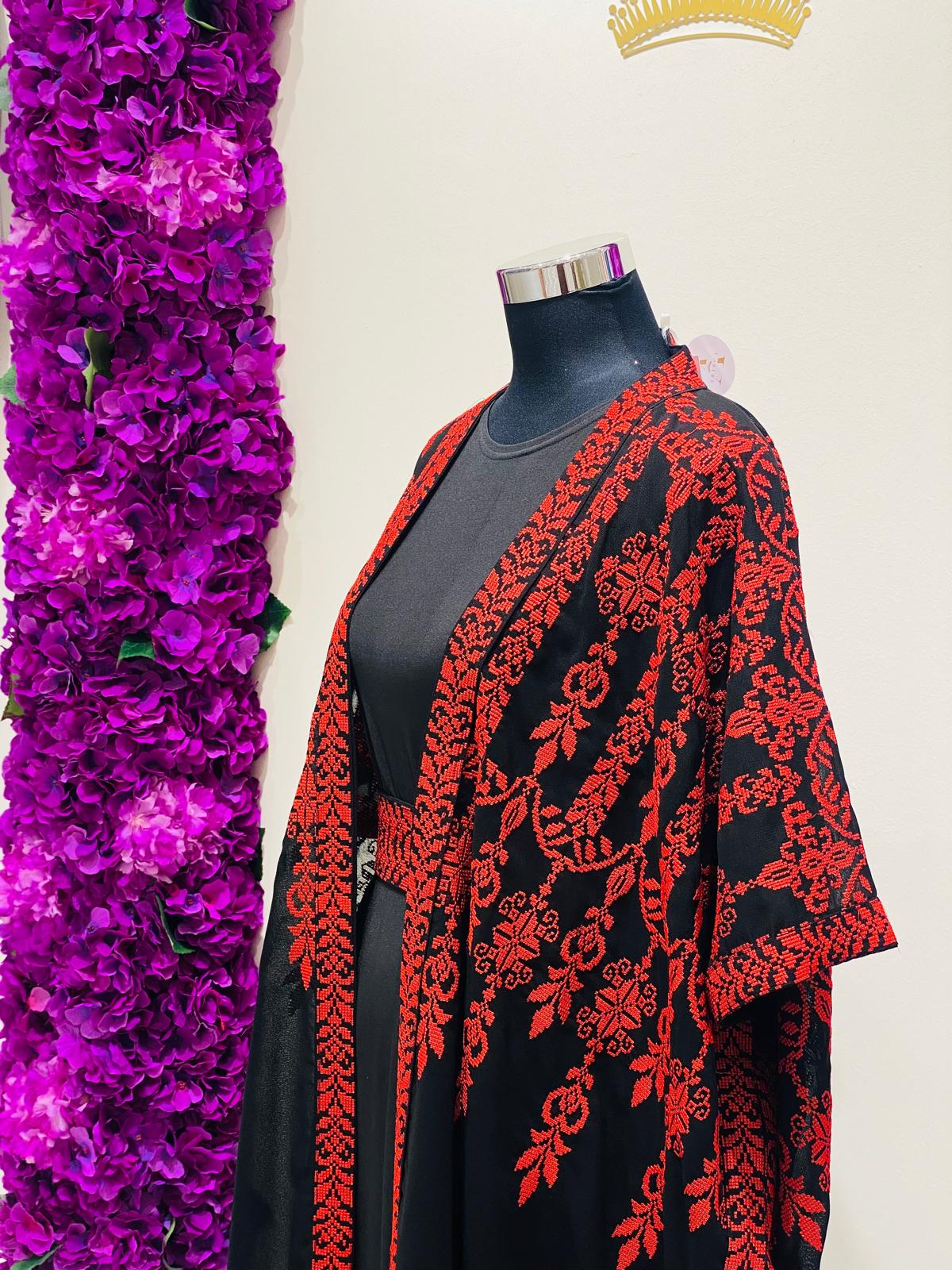 A black open-front kaftan or kimono-style cover-up with bold red floral embroidery.