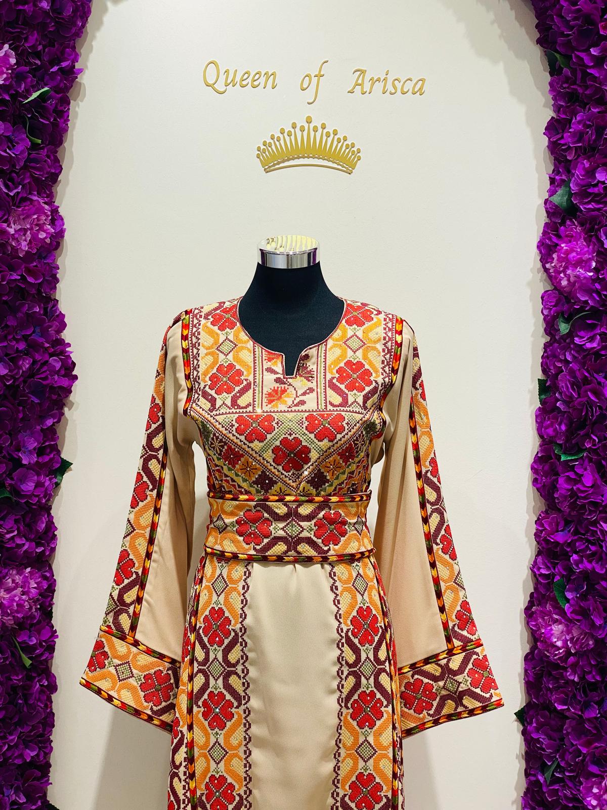 Champagne beige Palestinian-inspired thobe with red and orange geometric embroidery at Arisca Qatar.