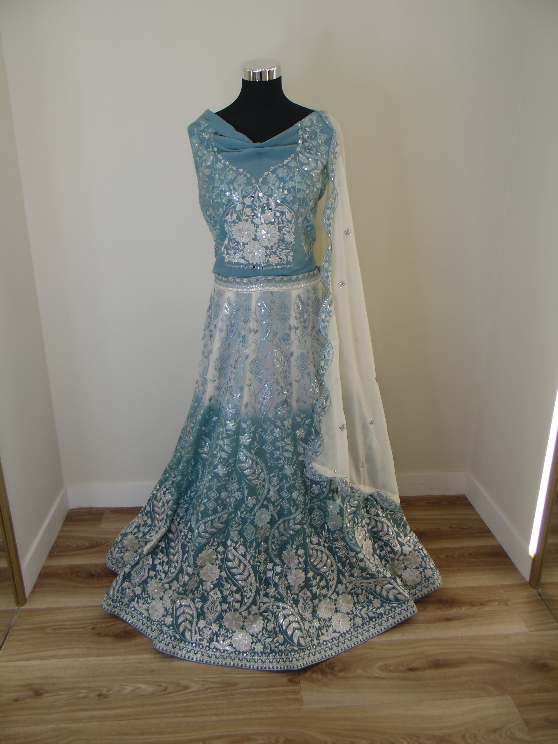 Blue embroidered Indian Lehenga on a mannequin against a white wall.