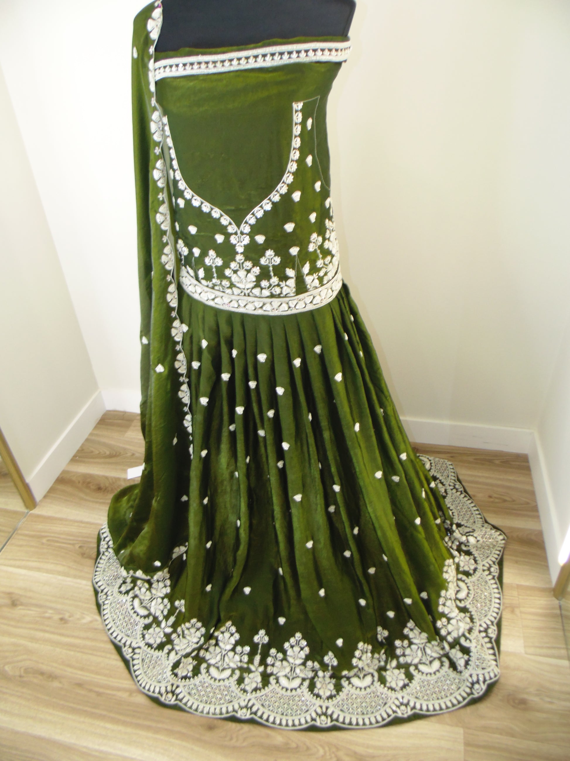 Green Lehenga with white hand embroidery on a wooden floor