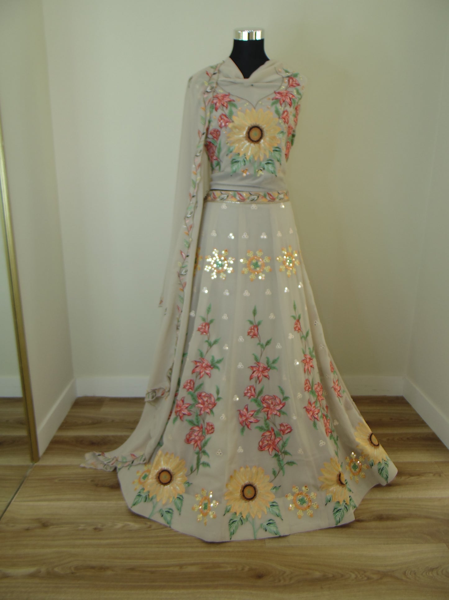 Floral Indian Lehenga with sunflower design hanging on a rack against a wooden wall.