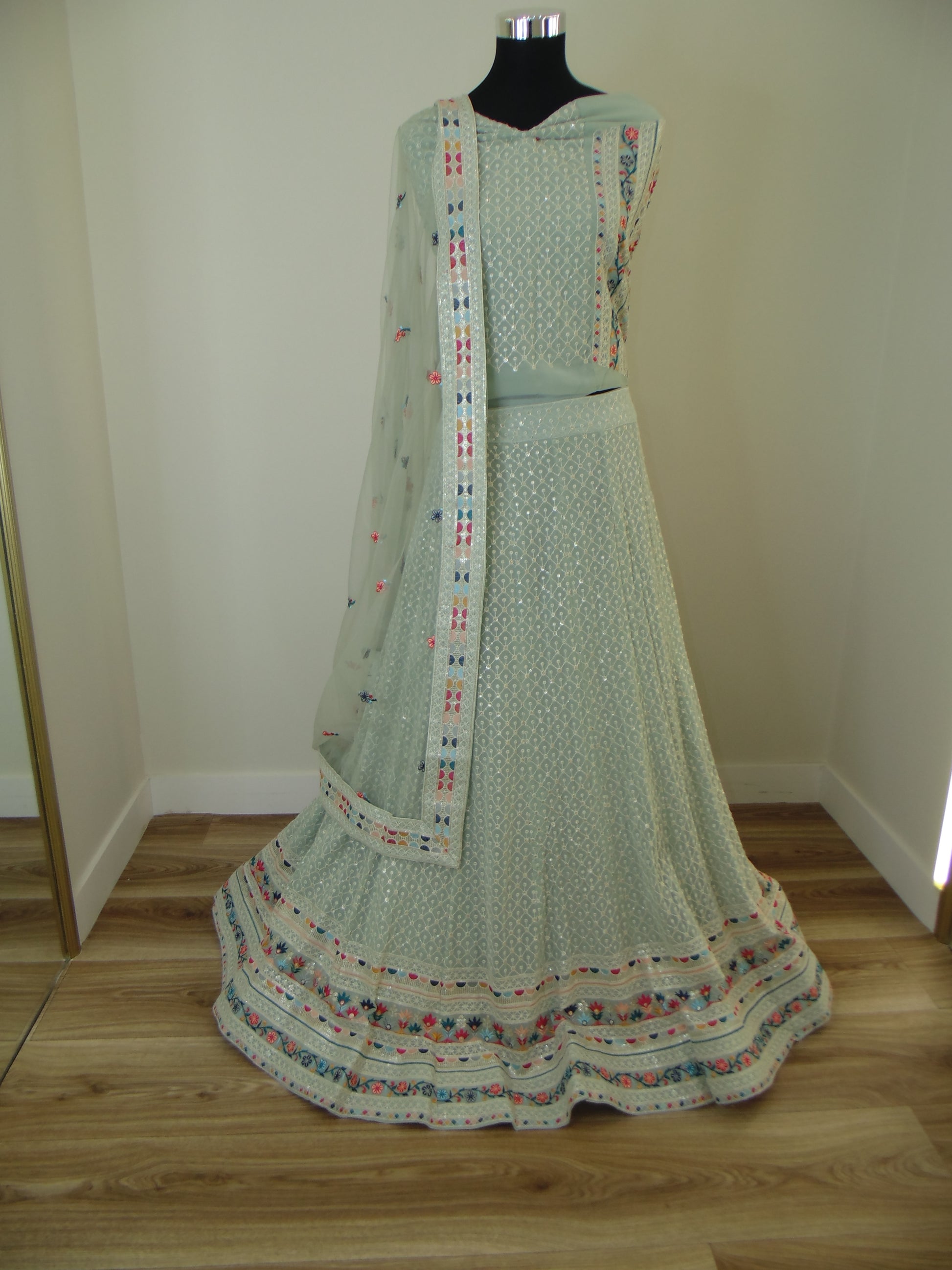 Light green dress with colorful trim on a mannequin against a neutral background