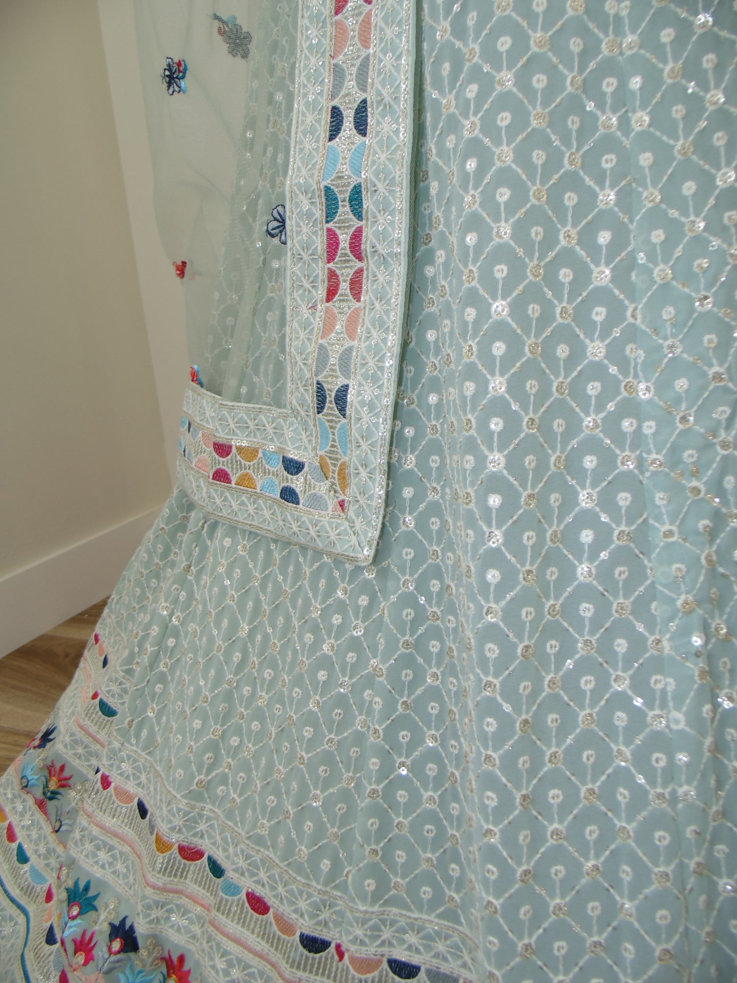 Light blue fabric with intricate patterns and colorful borders on a bed.