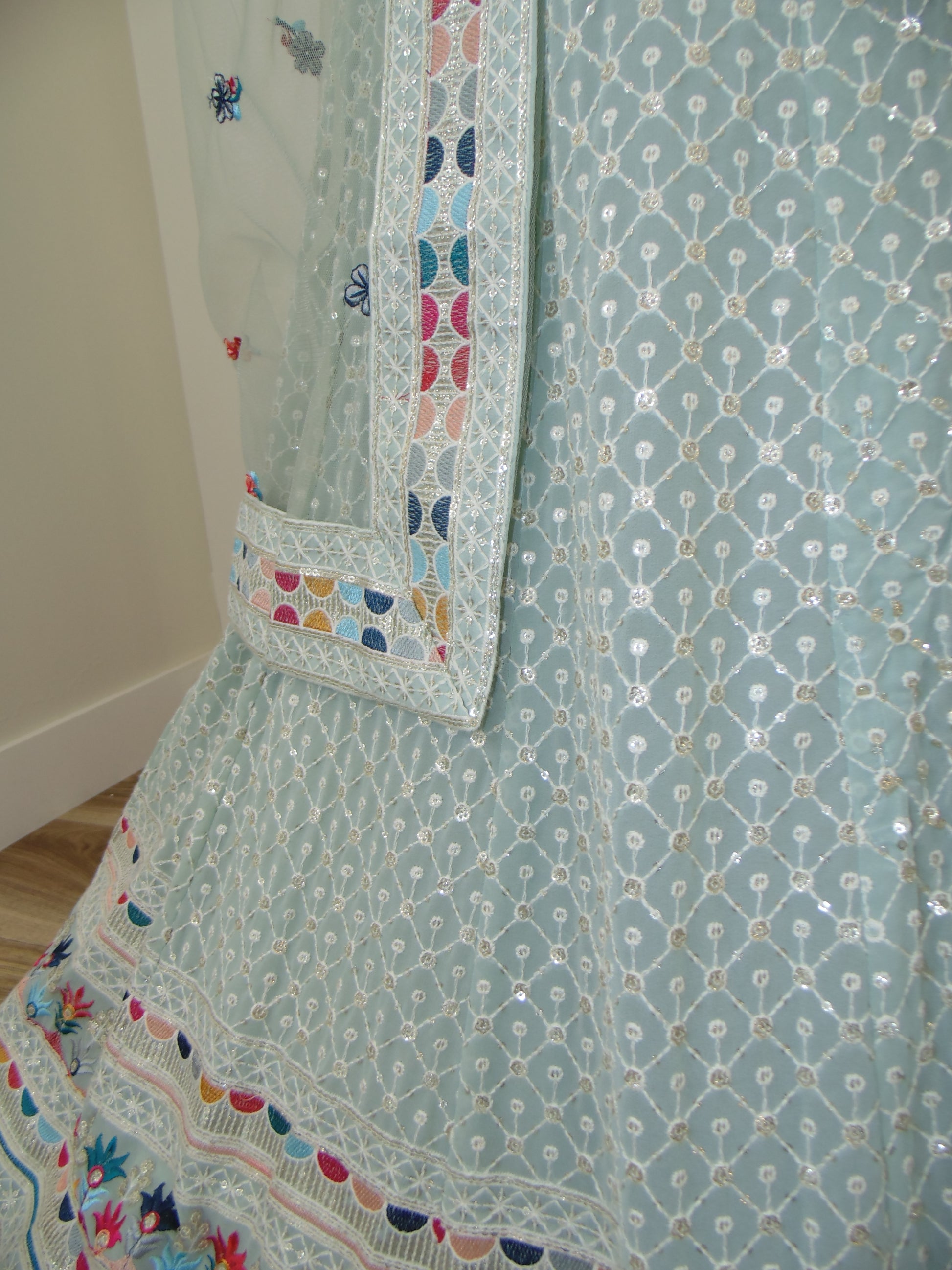 Light blue fabric with intricate patterns and colorful borders on a bed.