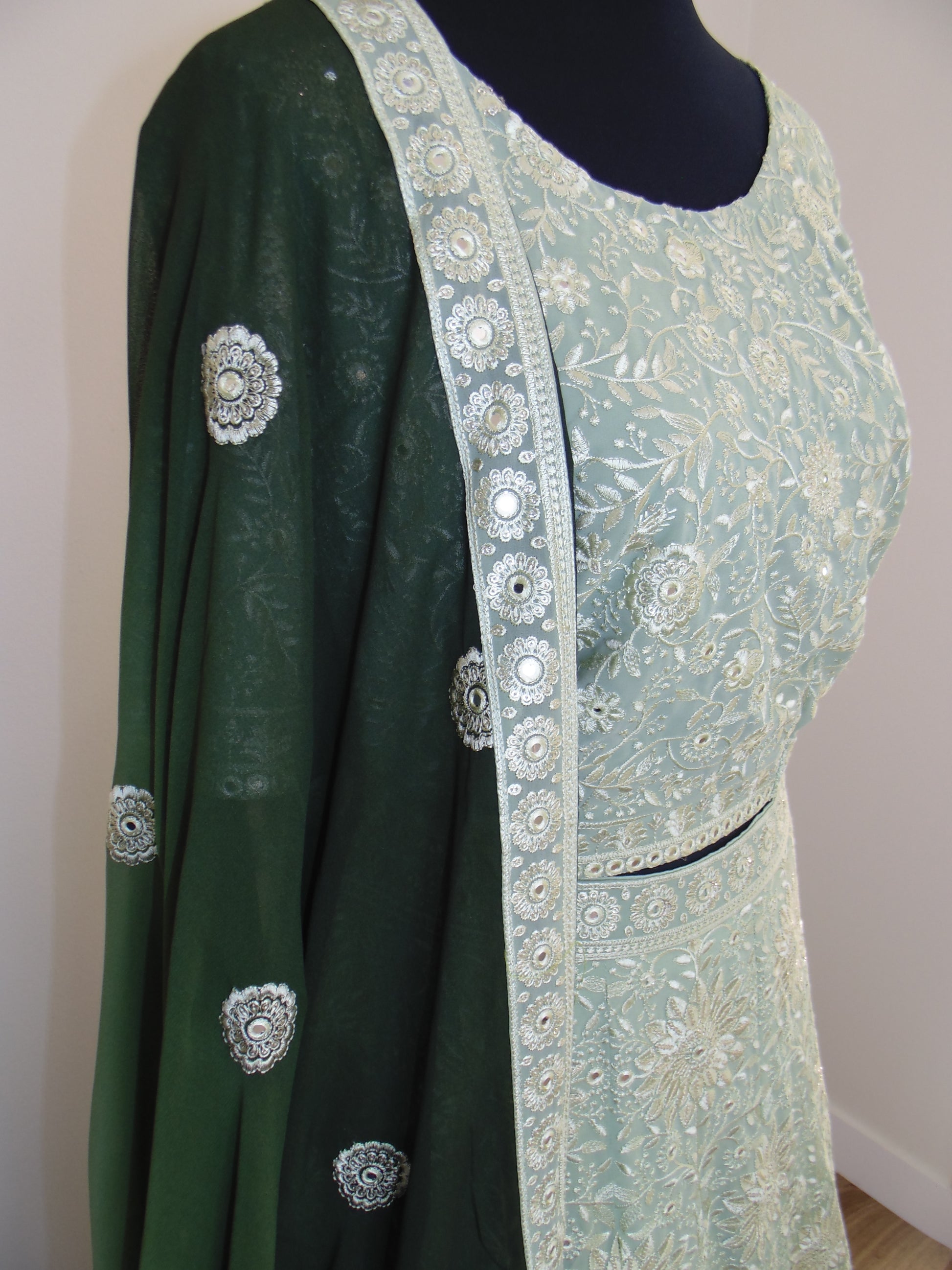 Green traditional outfit with intricate patterns on a white background