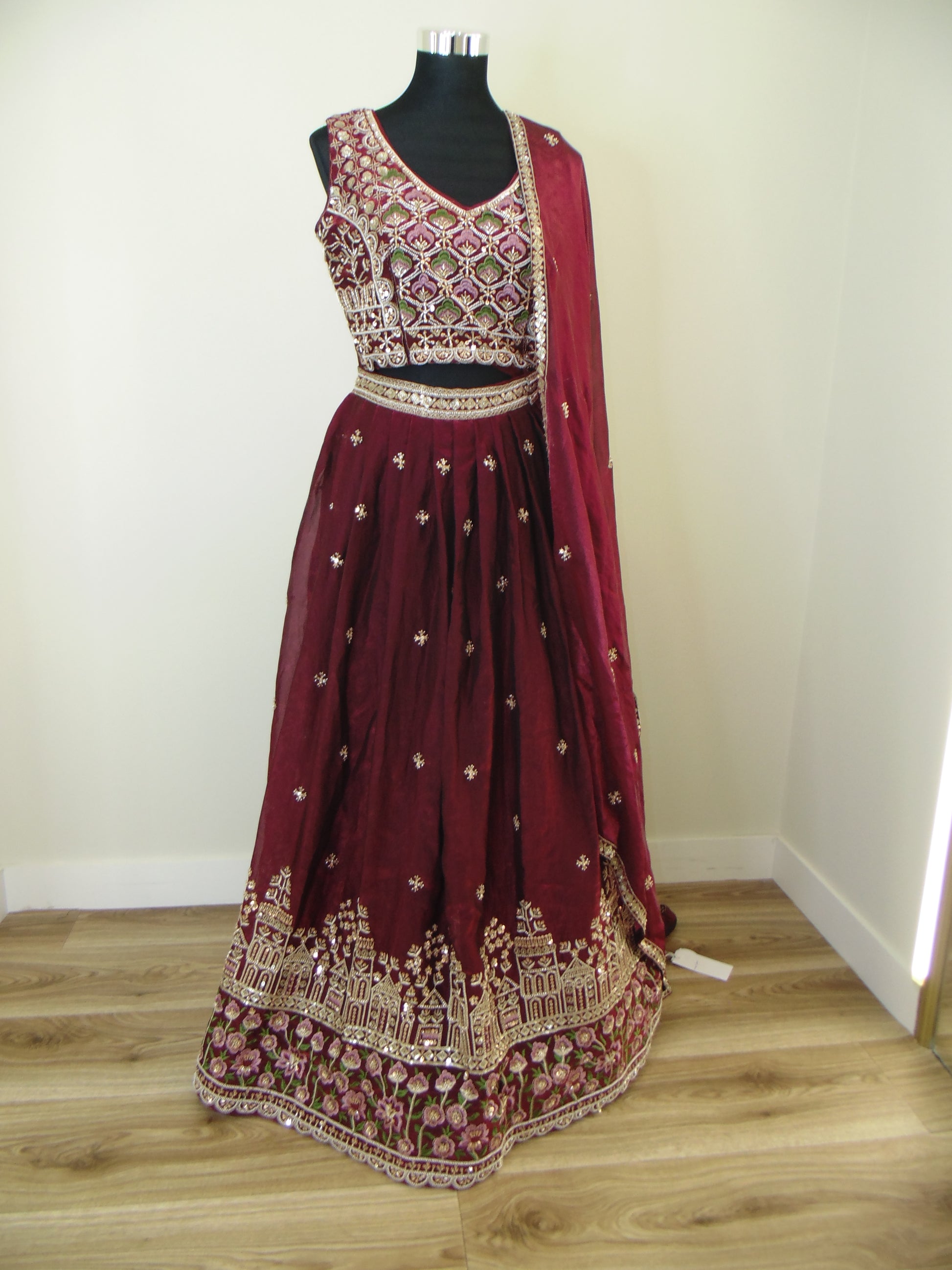 Maroon traditional outfit with gold embroidery on a white background