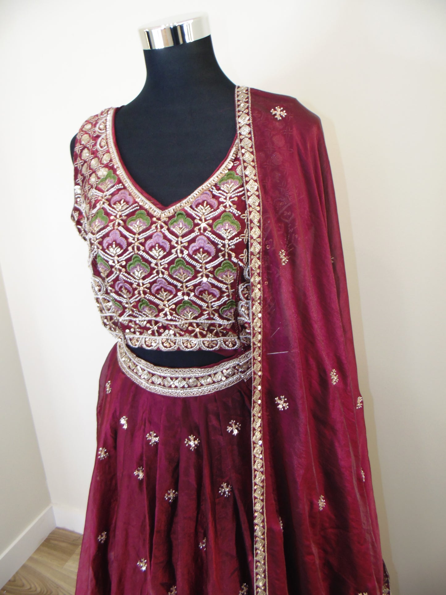 Maroon traditional outfit with intricate embroidery on a white background